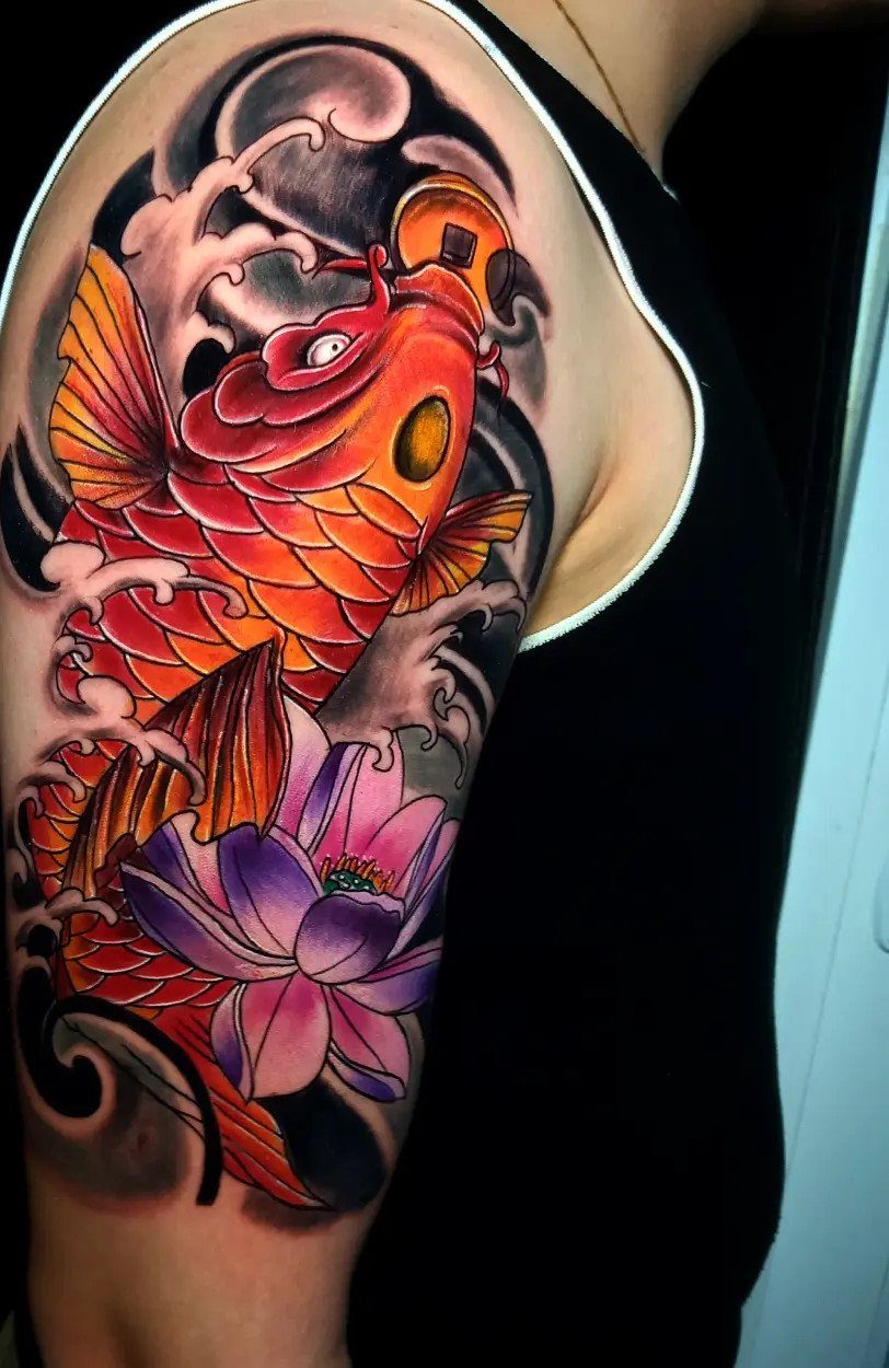 Colorful koi fish and purple lotus flower tattoo on a person's upper arm