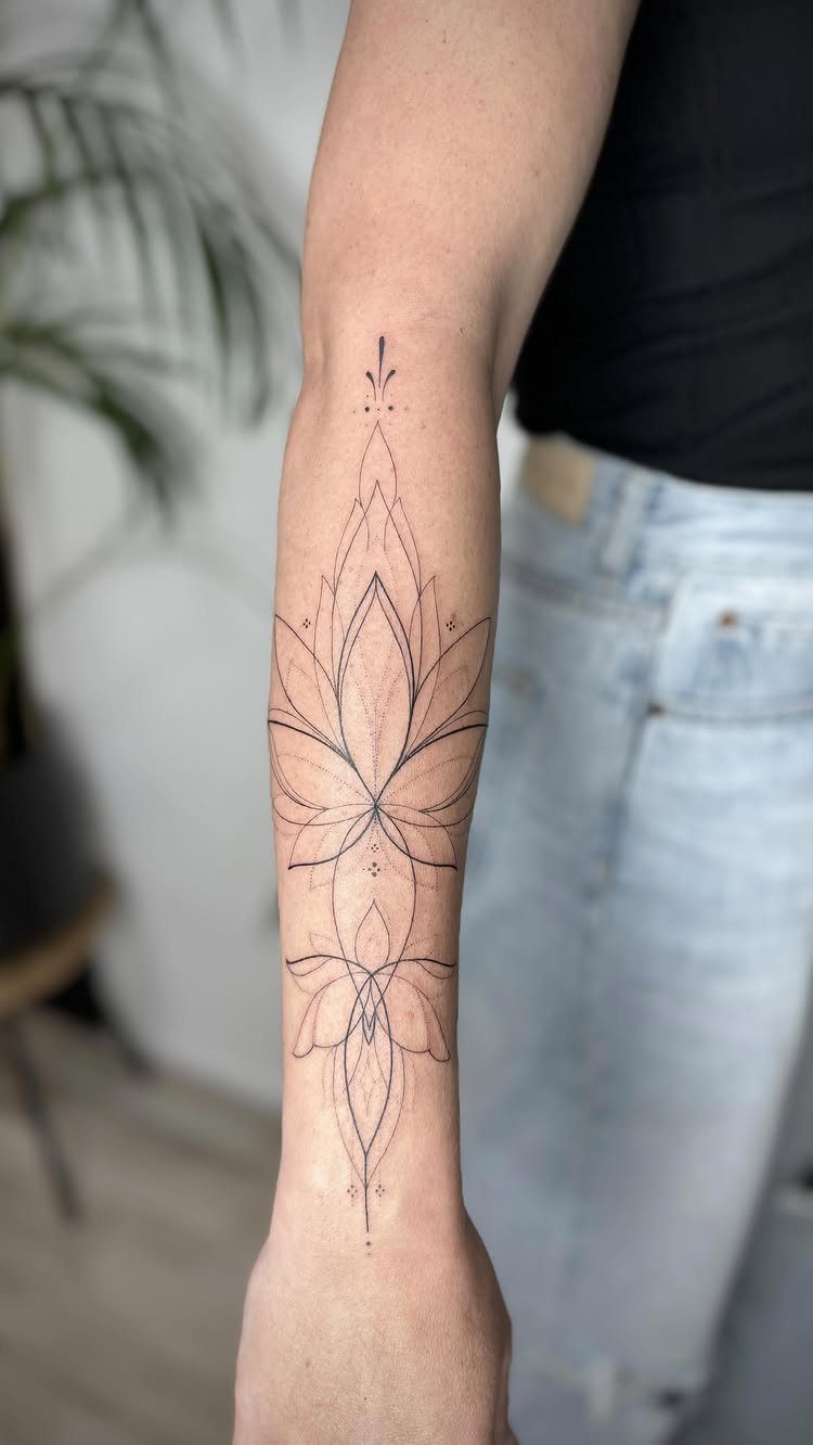 Fine-line lotus flower mandala tattoo on a person's forearm with symmetrical geometric patterns.