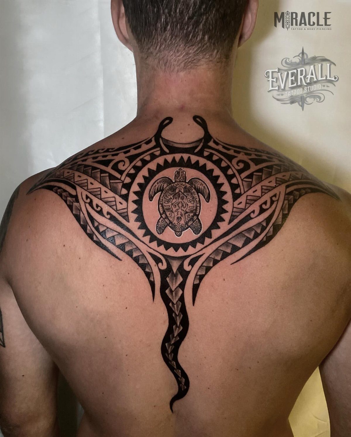 Tribal manta ray tattoo with a sea turtle on a man's upper back