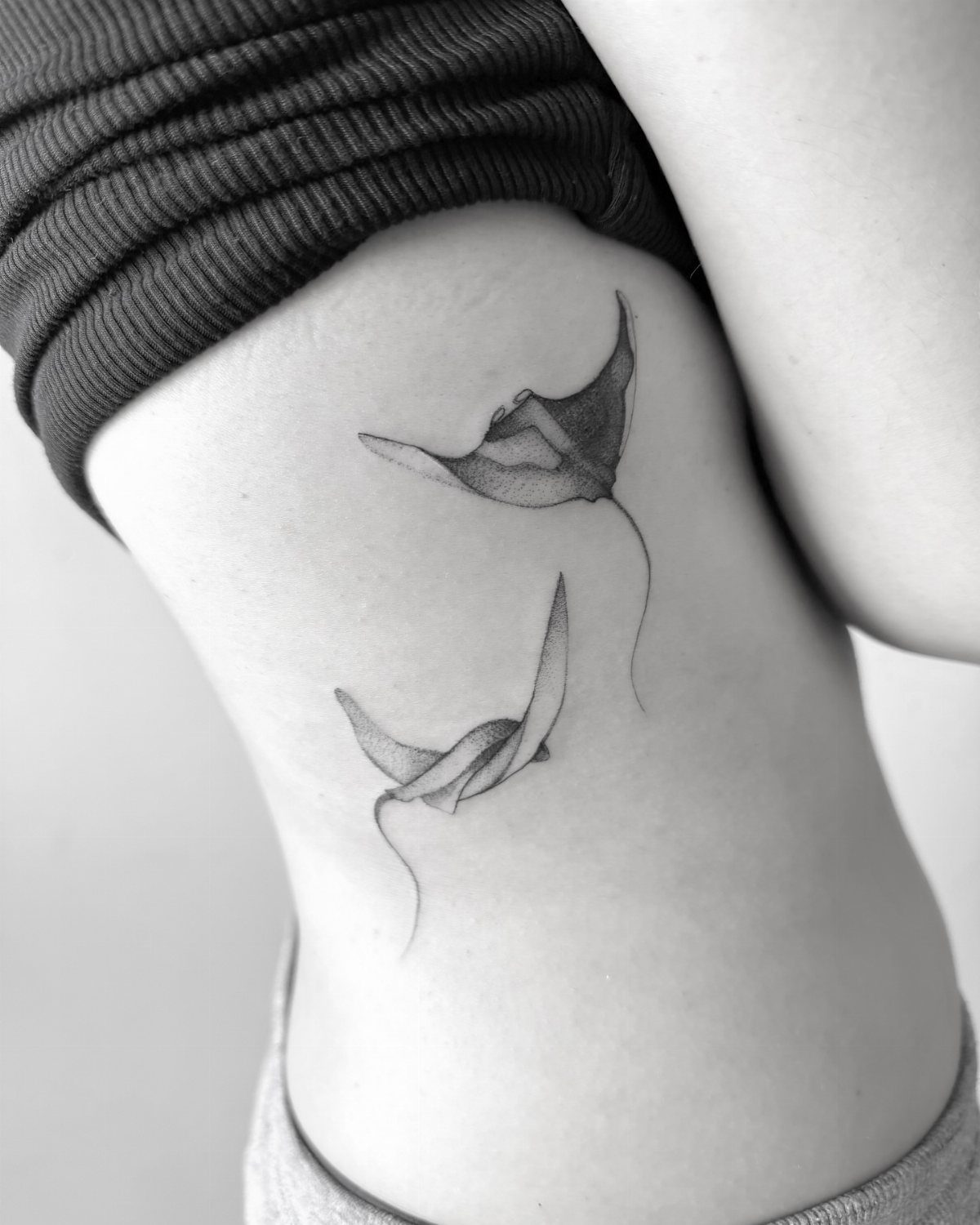 Two manta ray tattoos on the side of a person's torso.