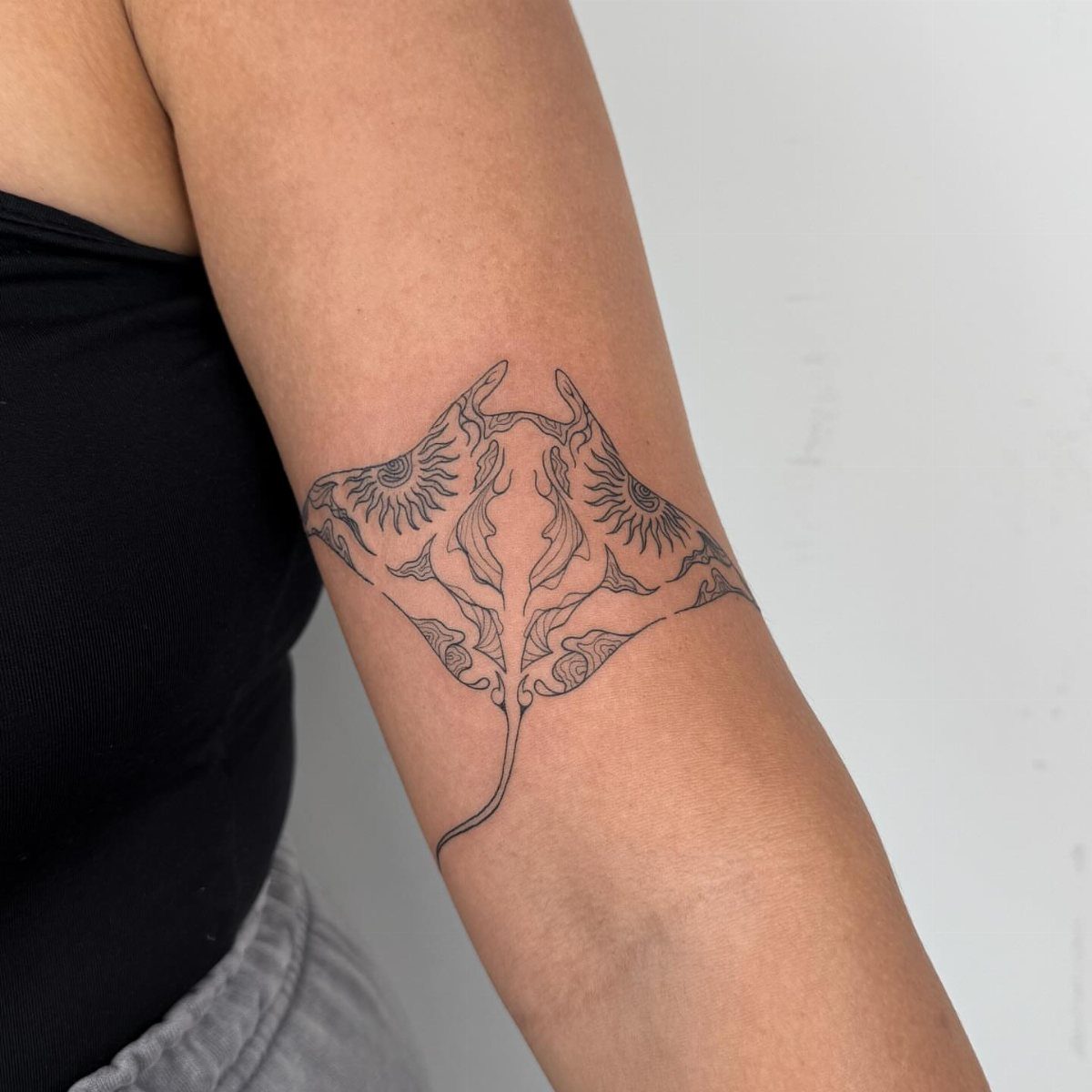 Manta ray tattoo with detailed patterns on a person's upper arm biceps.
