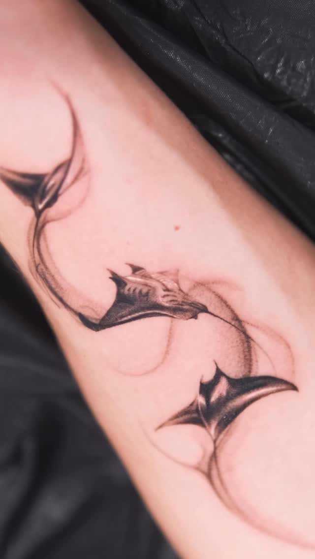 Manta ray tattoo on a forearm with flowing water current details in black ink