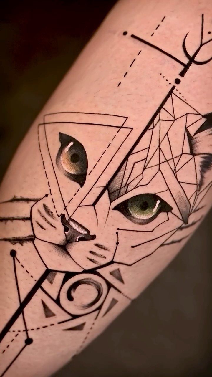 Geometric cat tattoo on skin with detailed green eyes and sharp black lines.