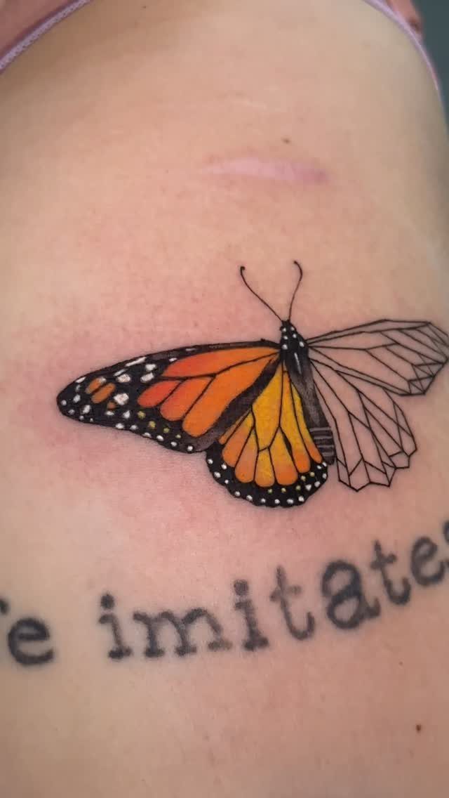 Monarch butterfly tattoo with one orange wing and one geometric white wing.