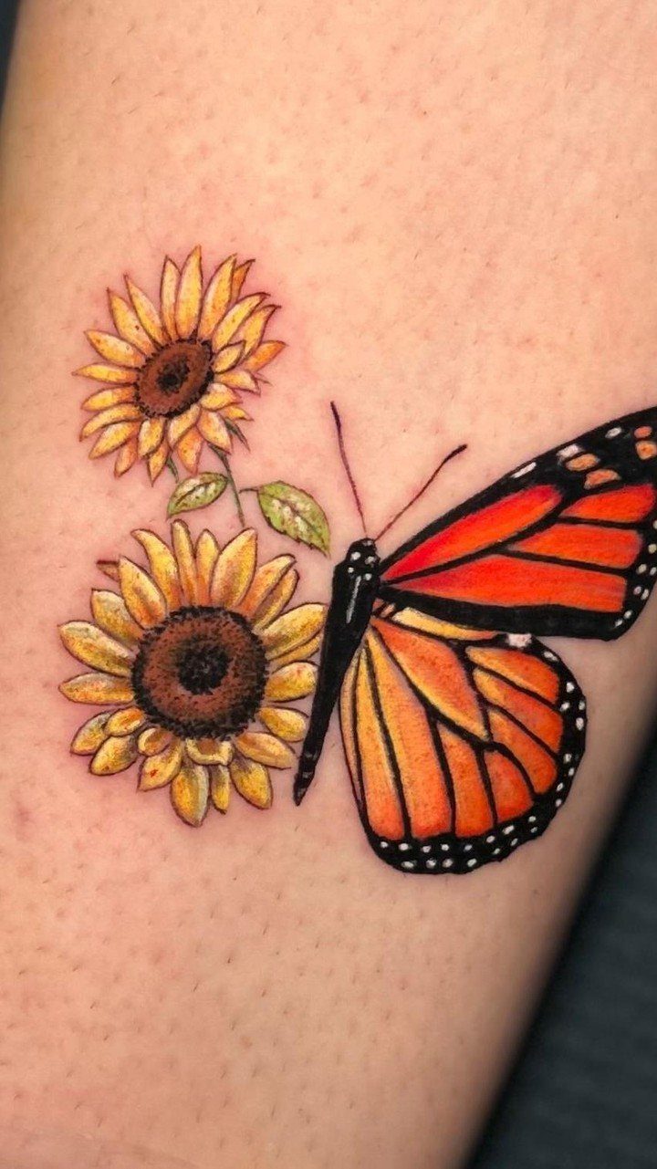 Monarch butterfly tattoo perched next to two bright yellow sunflowers on skin