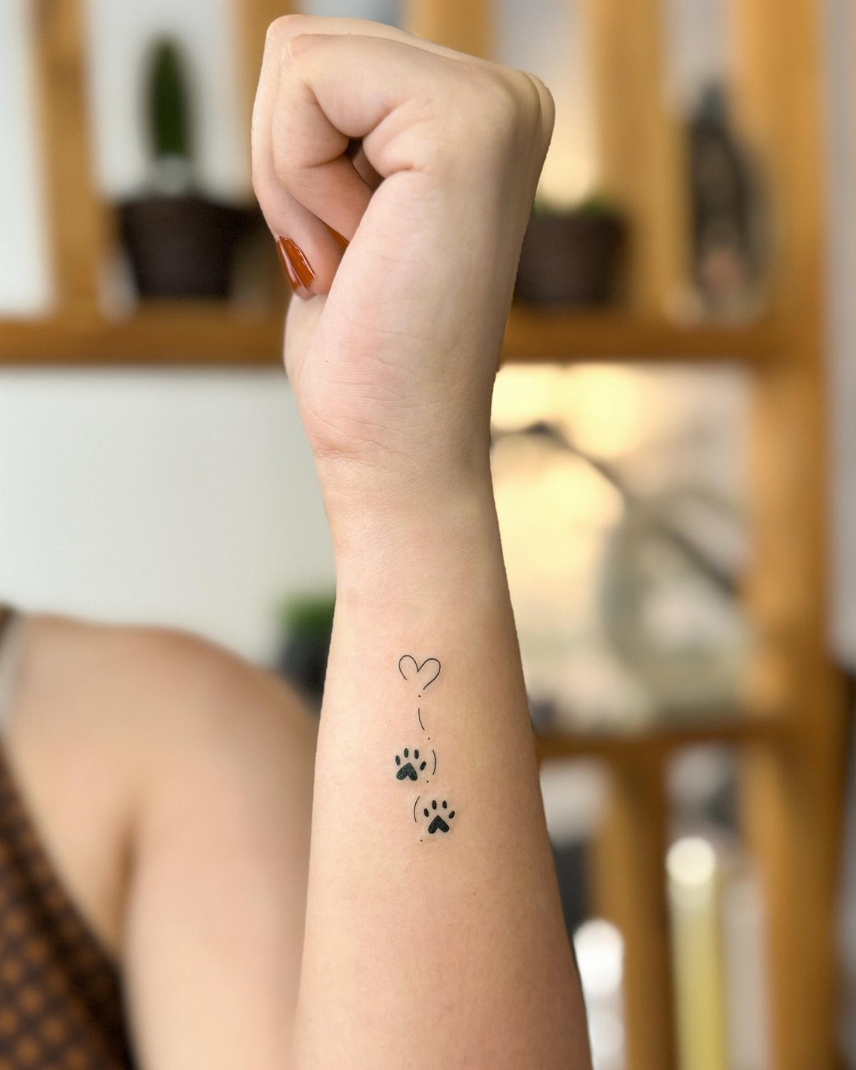 Small black heart and paw print tattoos on a person's inner wrist.