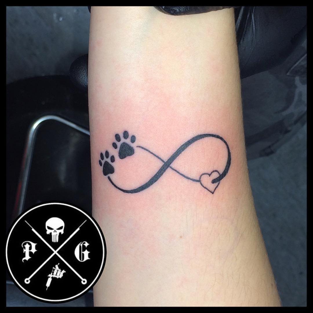 Infinity symbol tattoo with paw prints and a heart on a wrist.