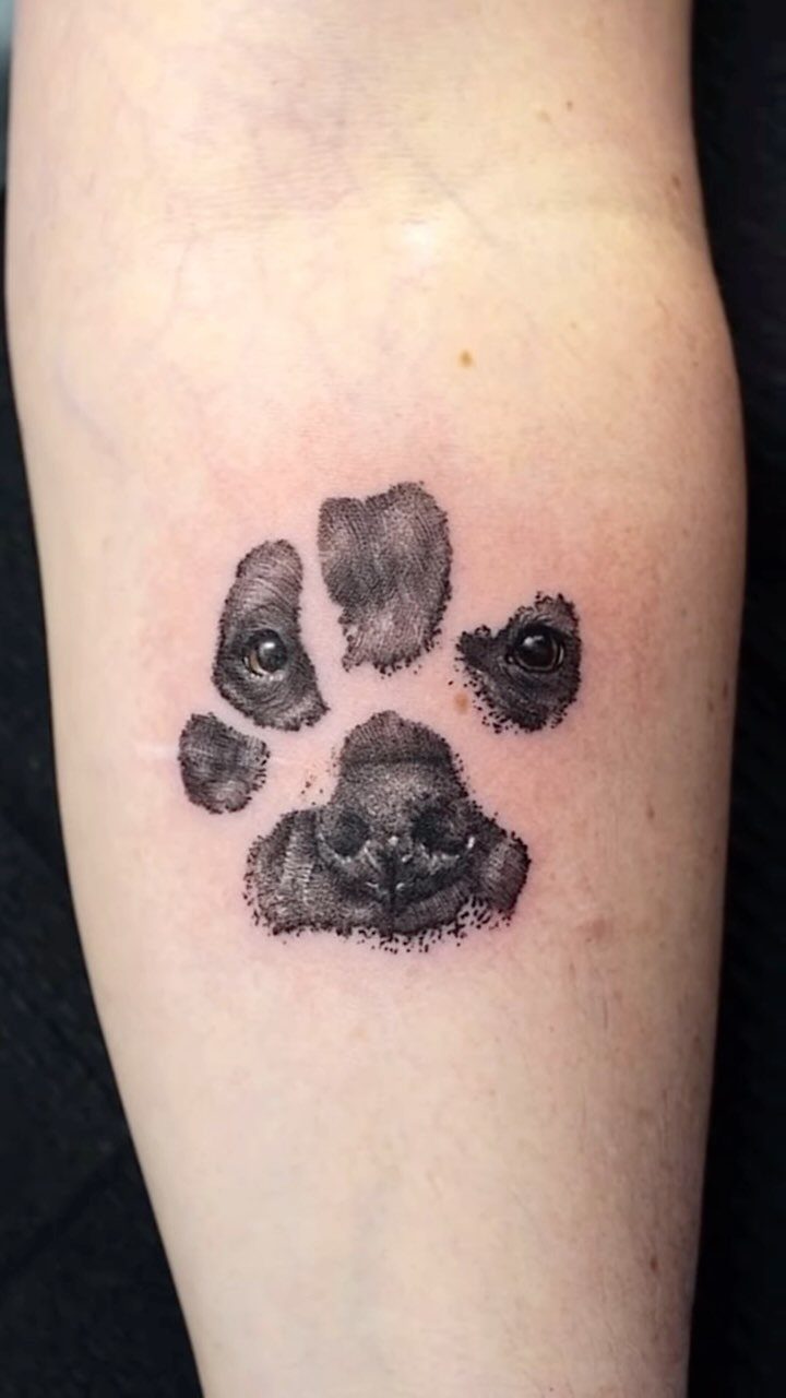 Paw print tattoo on a forearm featuring a dog portrait within the pads