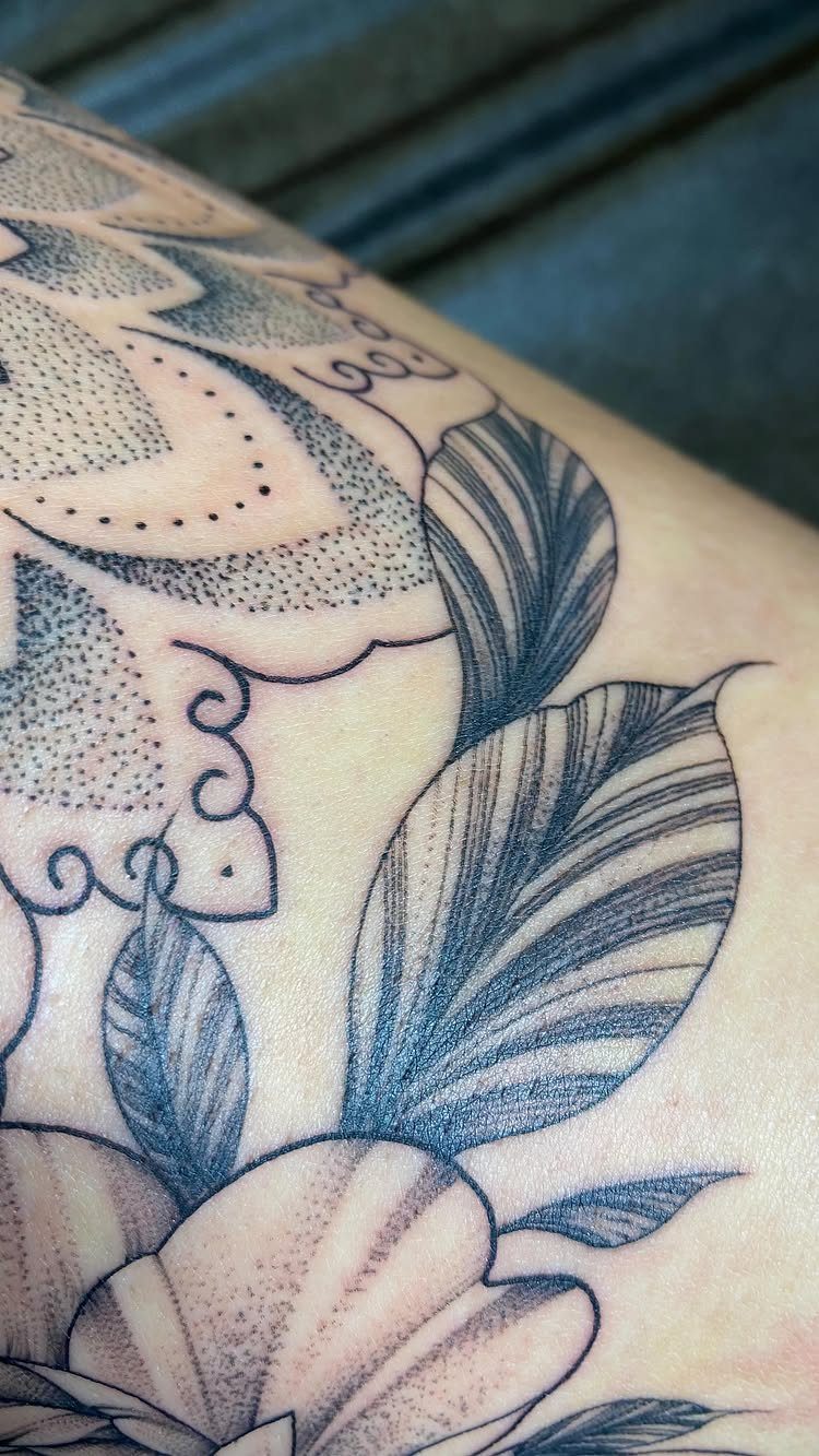 Peony flower and geometric mandala tattoo in black and gray ink on skin