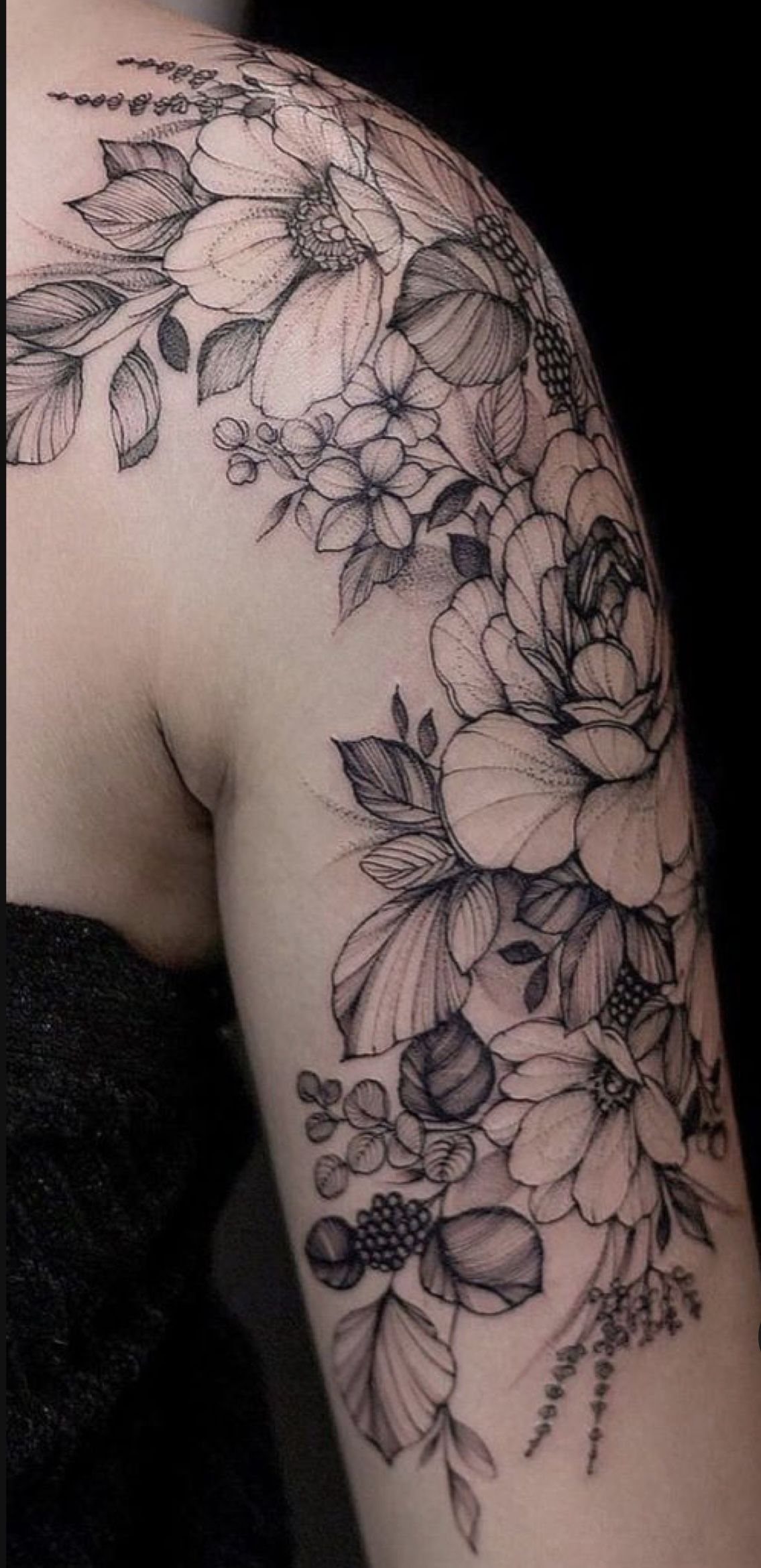 Botanical tattoo on an arm featuring peonies and wildflowers in black and gray ink.