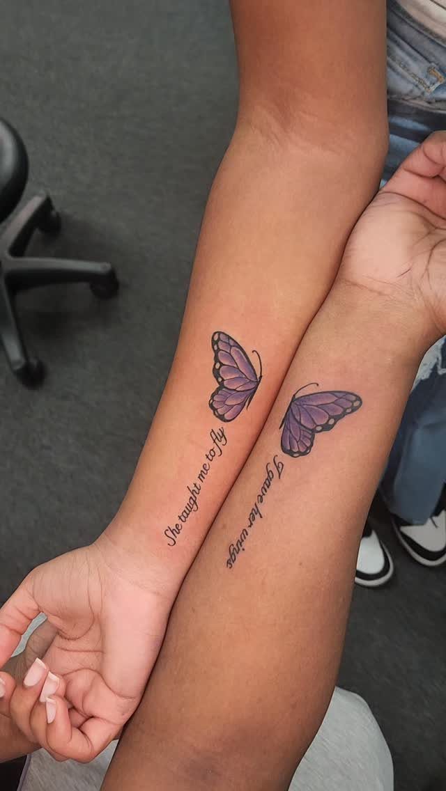 Two forearms with matching purple butterfly tattoos and cursive text forming one image.