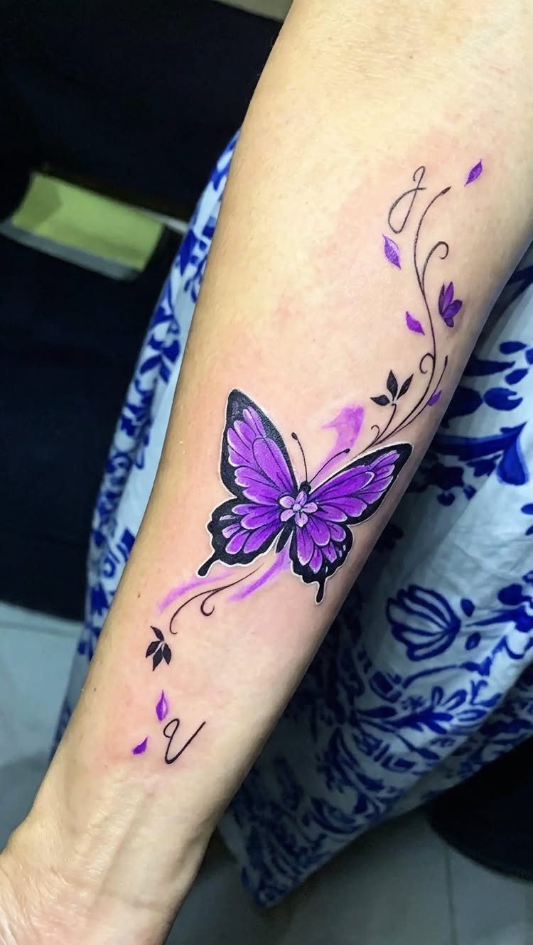 Purple butterfly tattoo with swirling black vines on a person's forearm