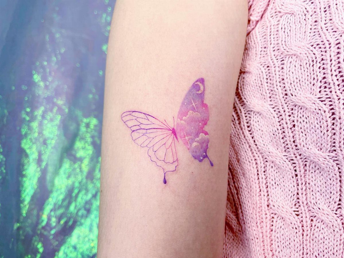 Purple butterfly tattoo on a forearm with one watercolor wing and one outline.
