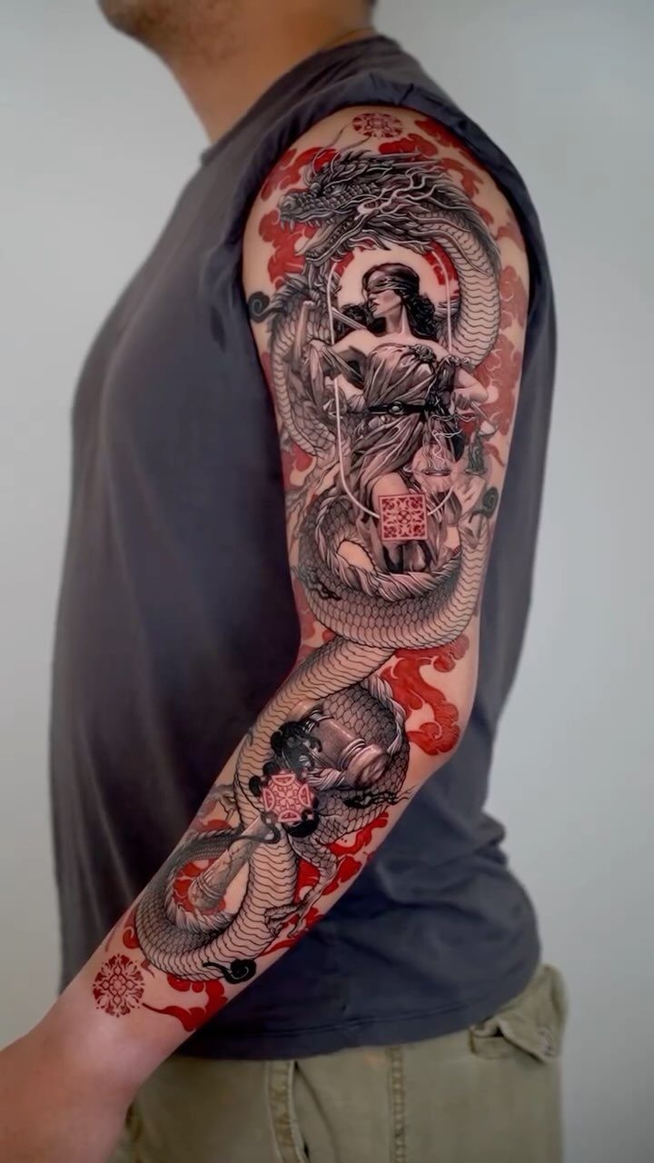Detailed sleeve tattoo of a red and black dragon with red clouds and woman.