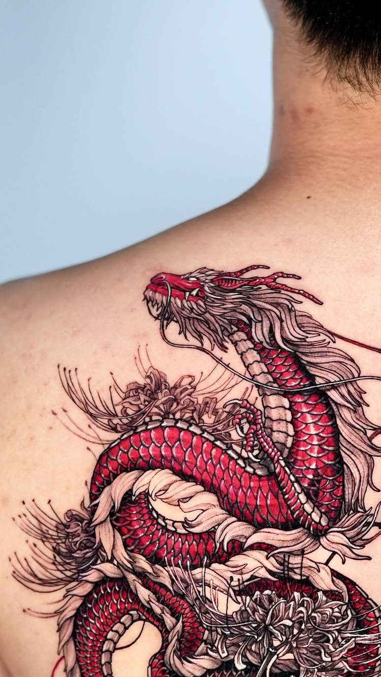 Red scaled dragon tattoo entwined with black and white spider lilies on a back