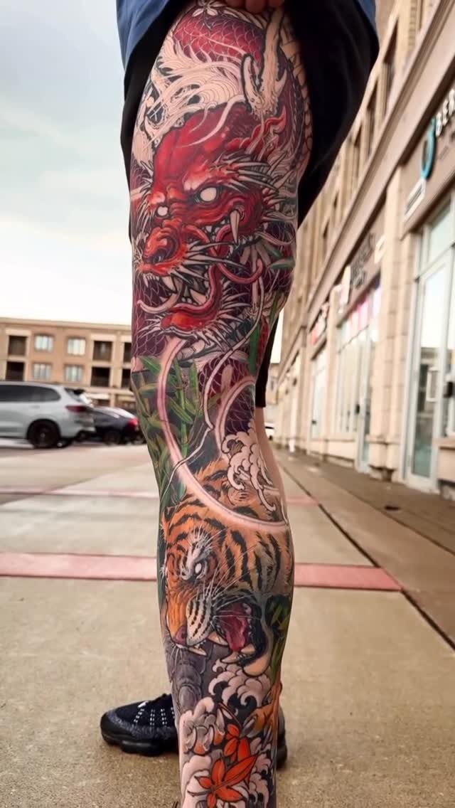 Leg sleeve tattoo featuring a red dragon on the thigh and orange tiger below.