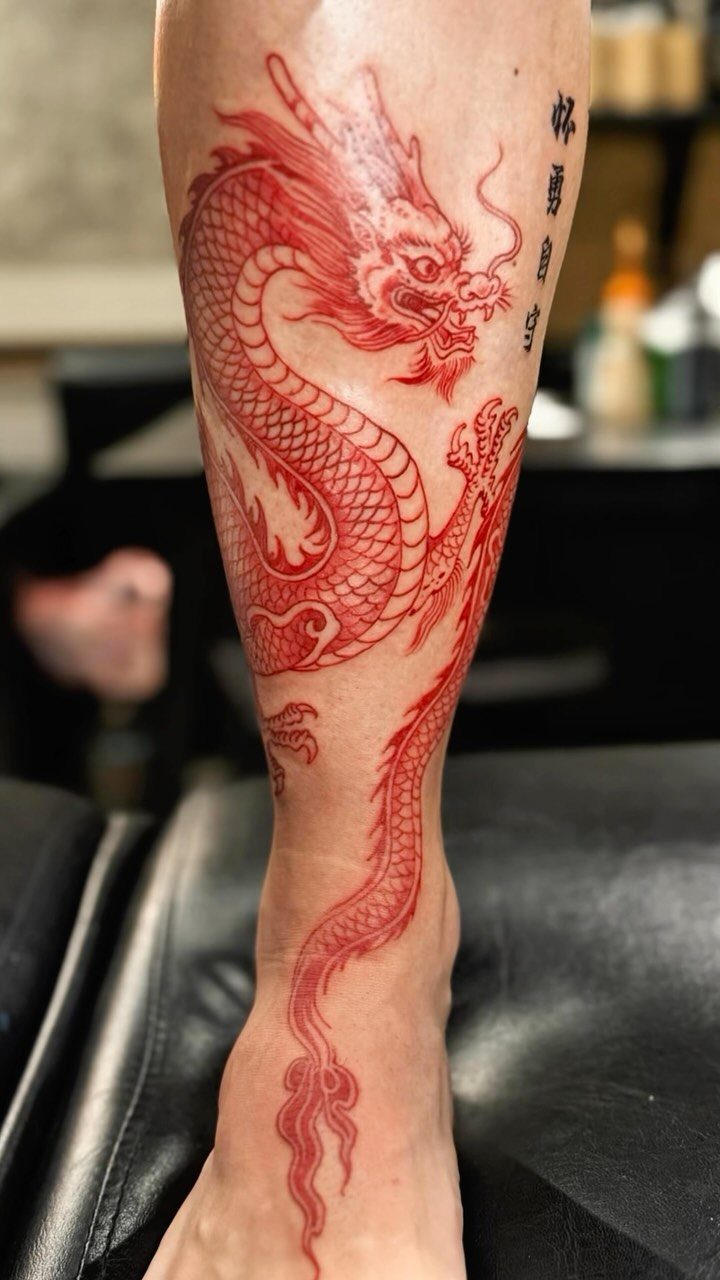 Red Chinese dragon tattoo winding down a person's lower leg and ankle.