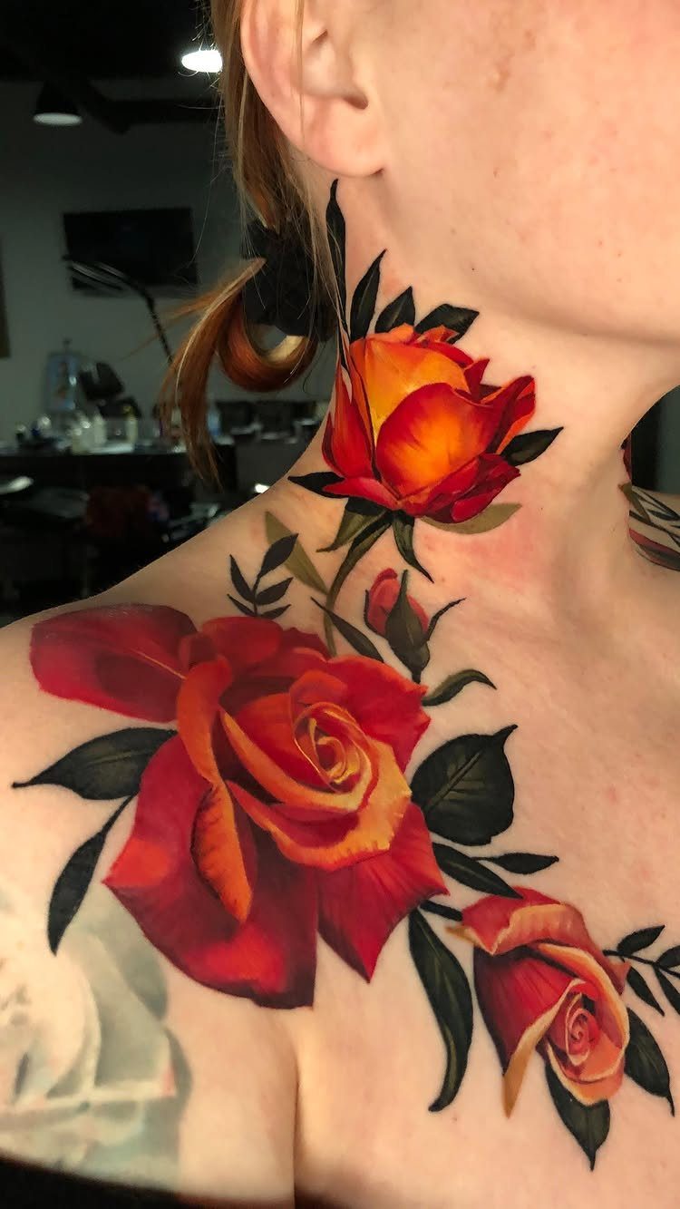 Red and orange rose tattoos with green leaves on a person's neck and shoulder.
