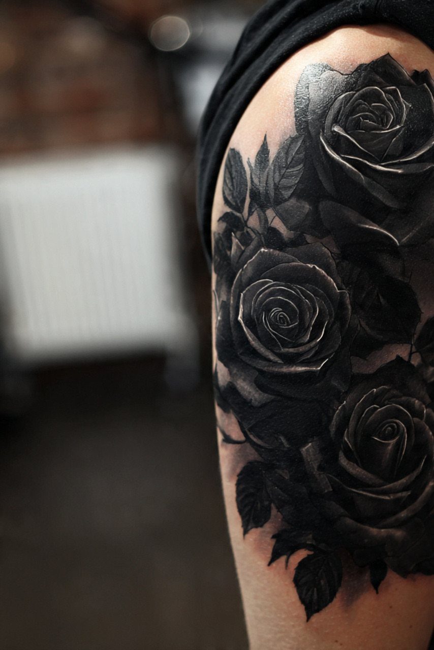 Black and grey rose tattoo on an upper arm with detailed shading.