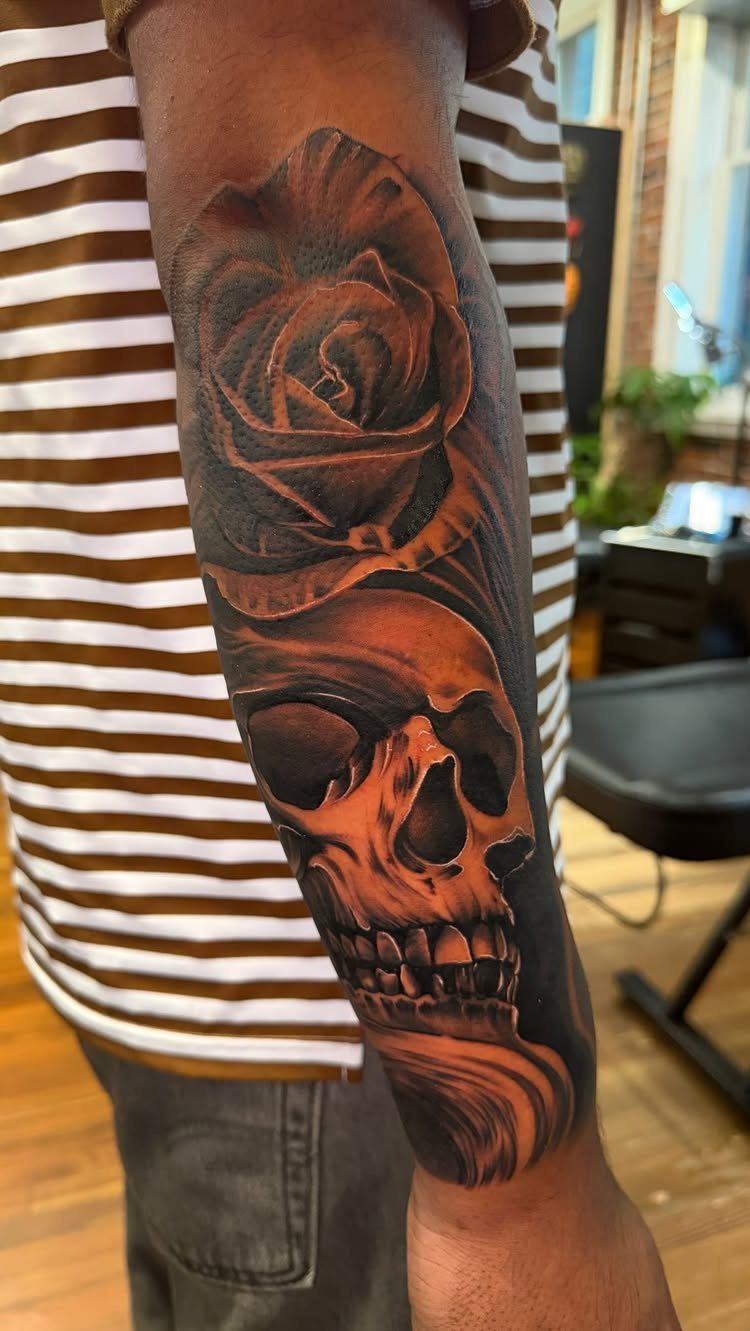 Rose and skull tattoo in black and grey ink on a forearm