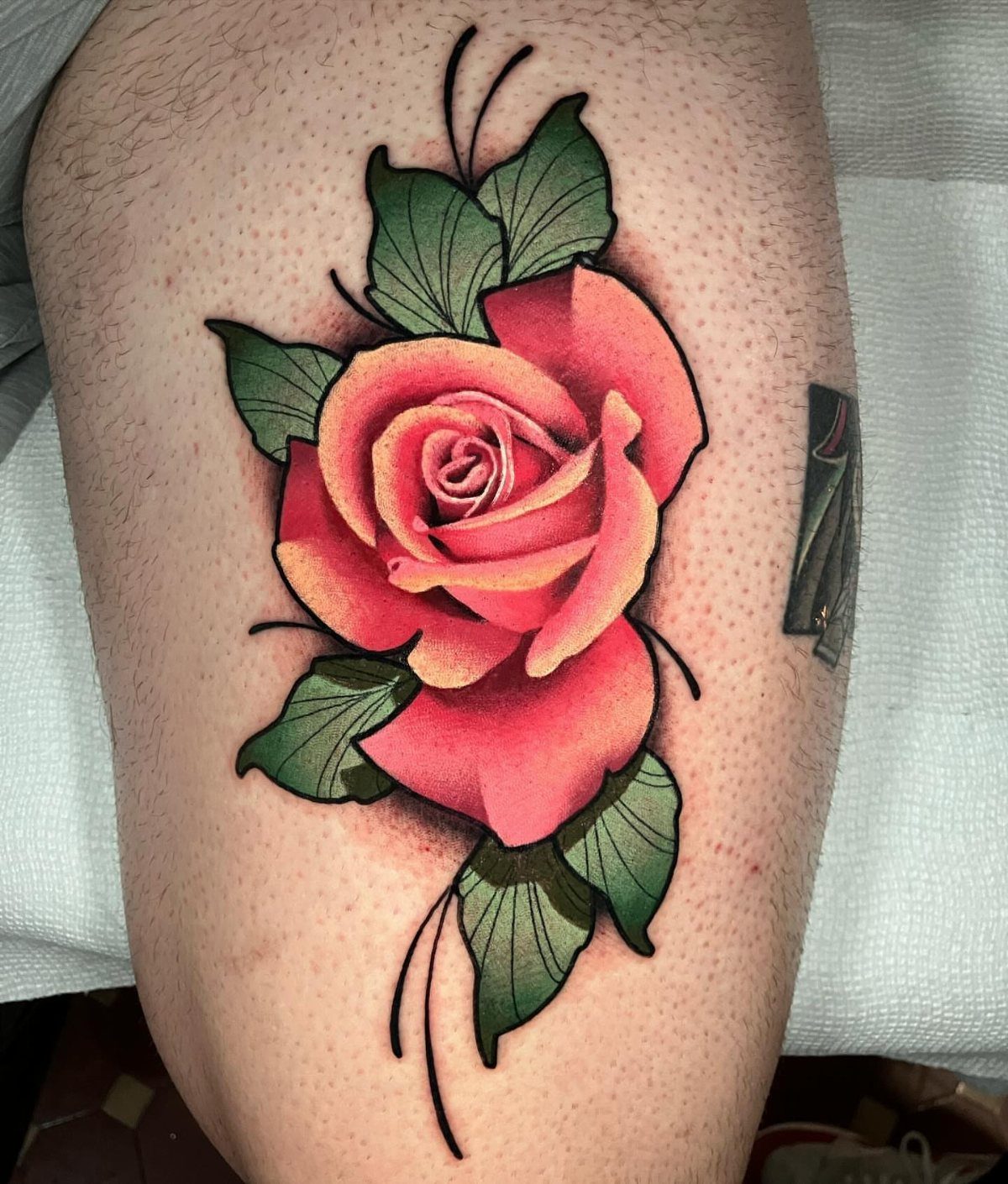 Red and yellow rose tattoo with green leaves and bold black outlines.