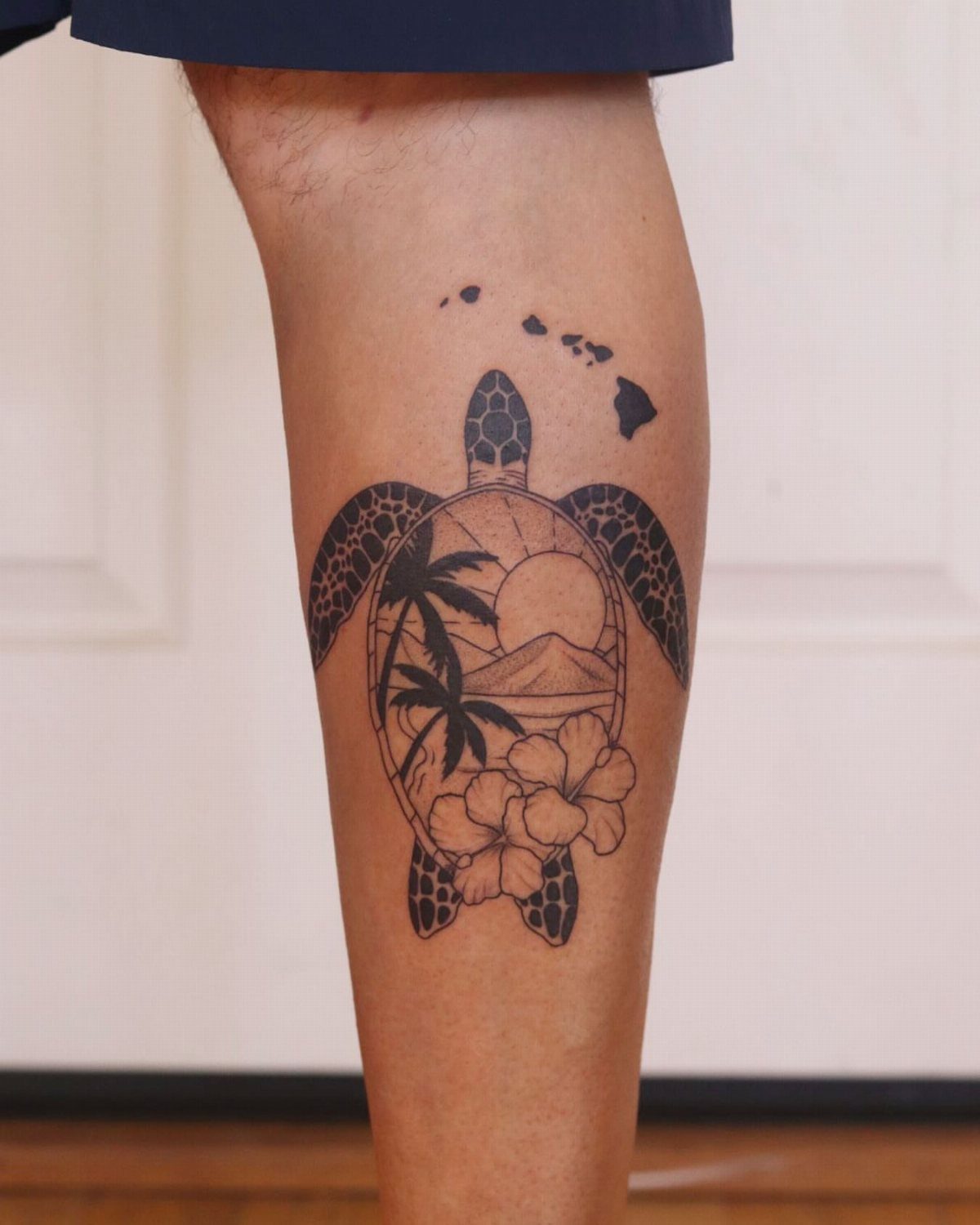 Sea turtle tattoo on a leg featuring a Hawaiian landscape and island chain.