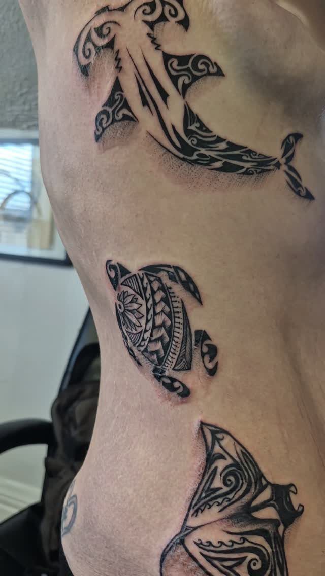 Tribal sea turtle tattoo with Polynesian patterns on a person's side.