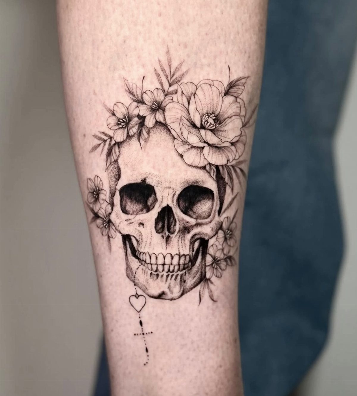 Skull tattoo with a floral crown of peonies on a person's arm