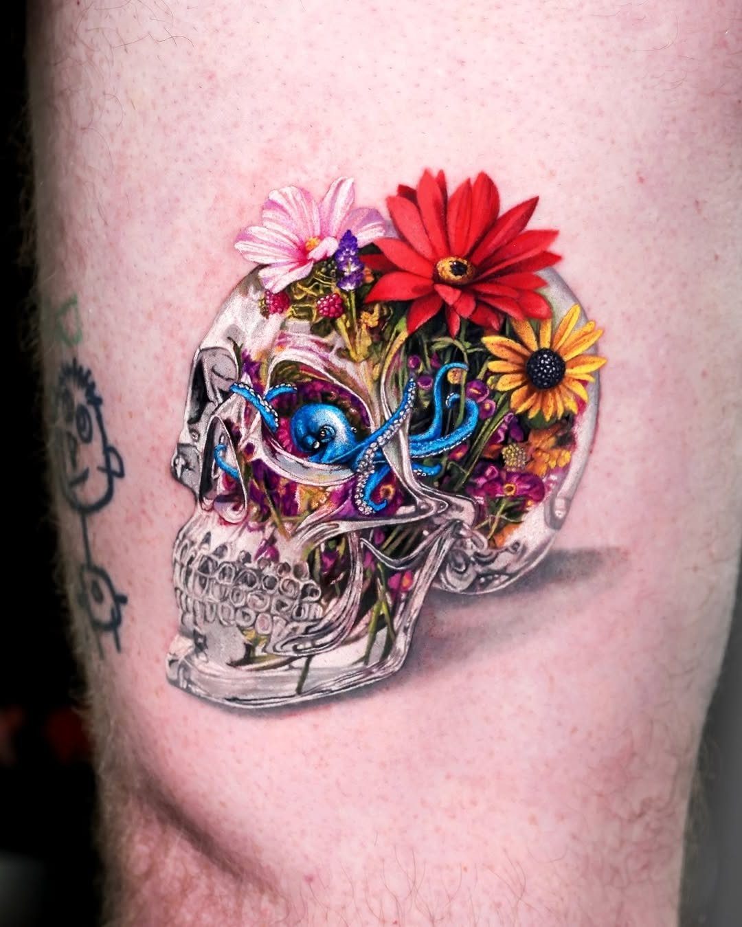 Transparent skull tattoo filled with colorful flowers and a small blue octopus