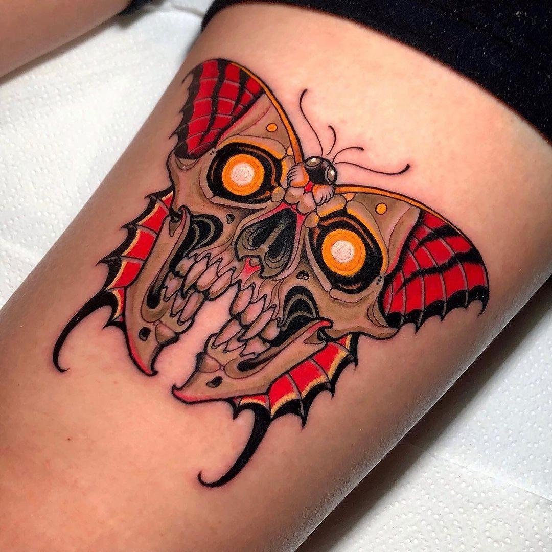Butterfly skull tattoo with red wings and yellow eyes on human skin