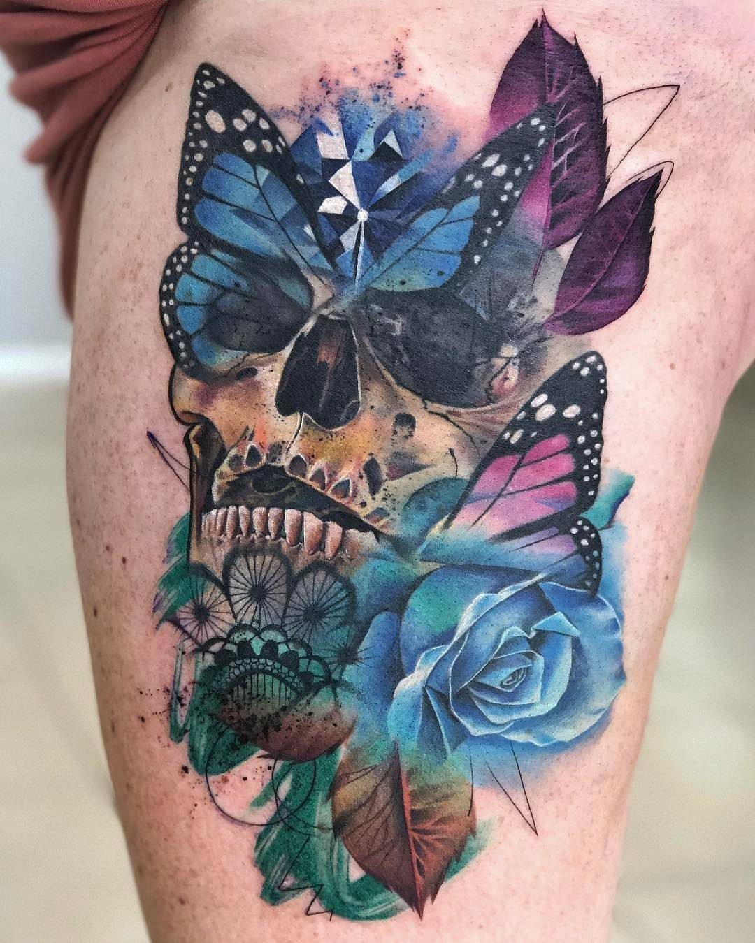 Colorful tattoo of a skull with blue butterflies and a blue rose