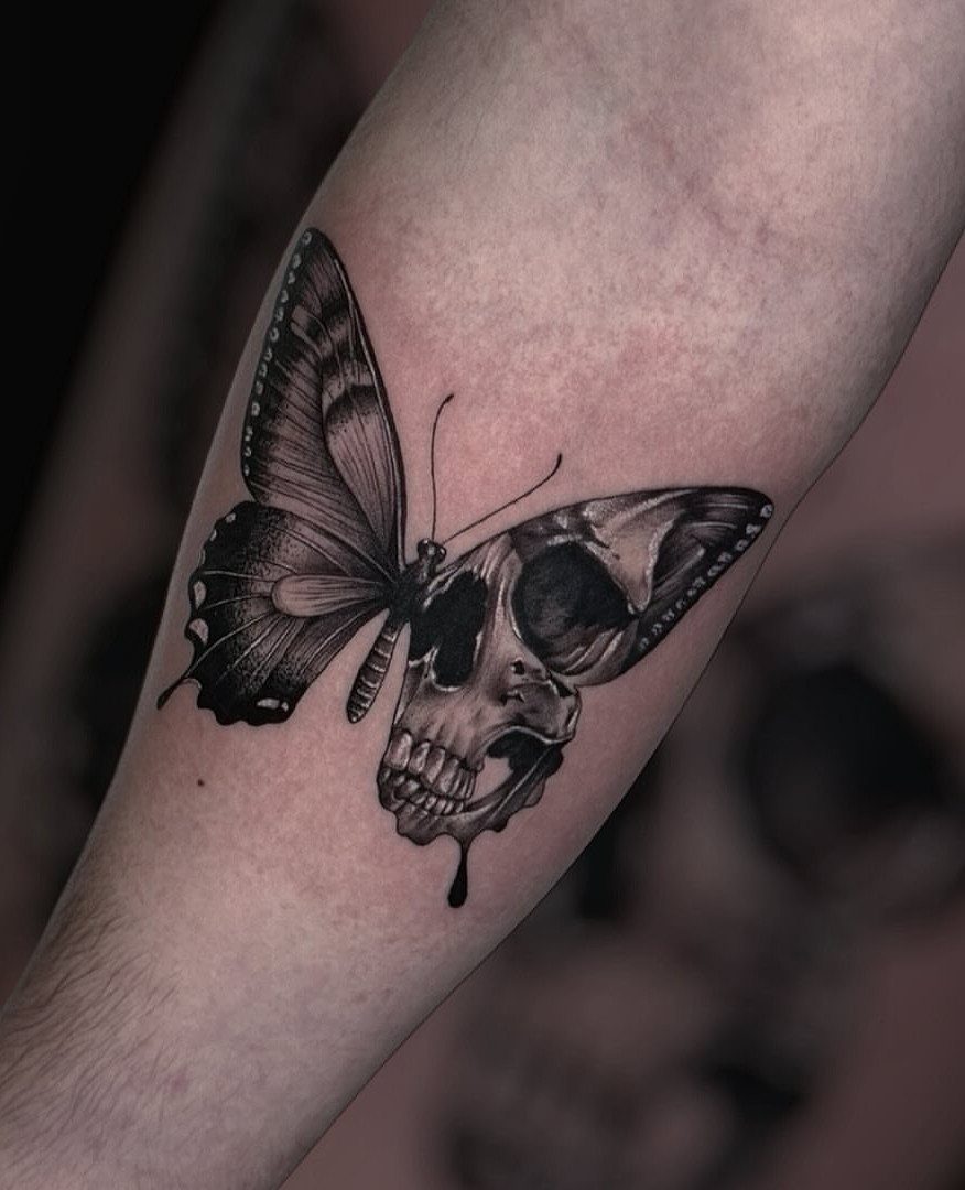 Butterfly skull tattoo on a forearm with one wing replacing half the skull