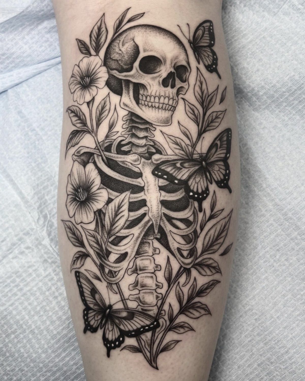 Skeleton tattoo with butterflies and flowers on a person's skin