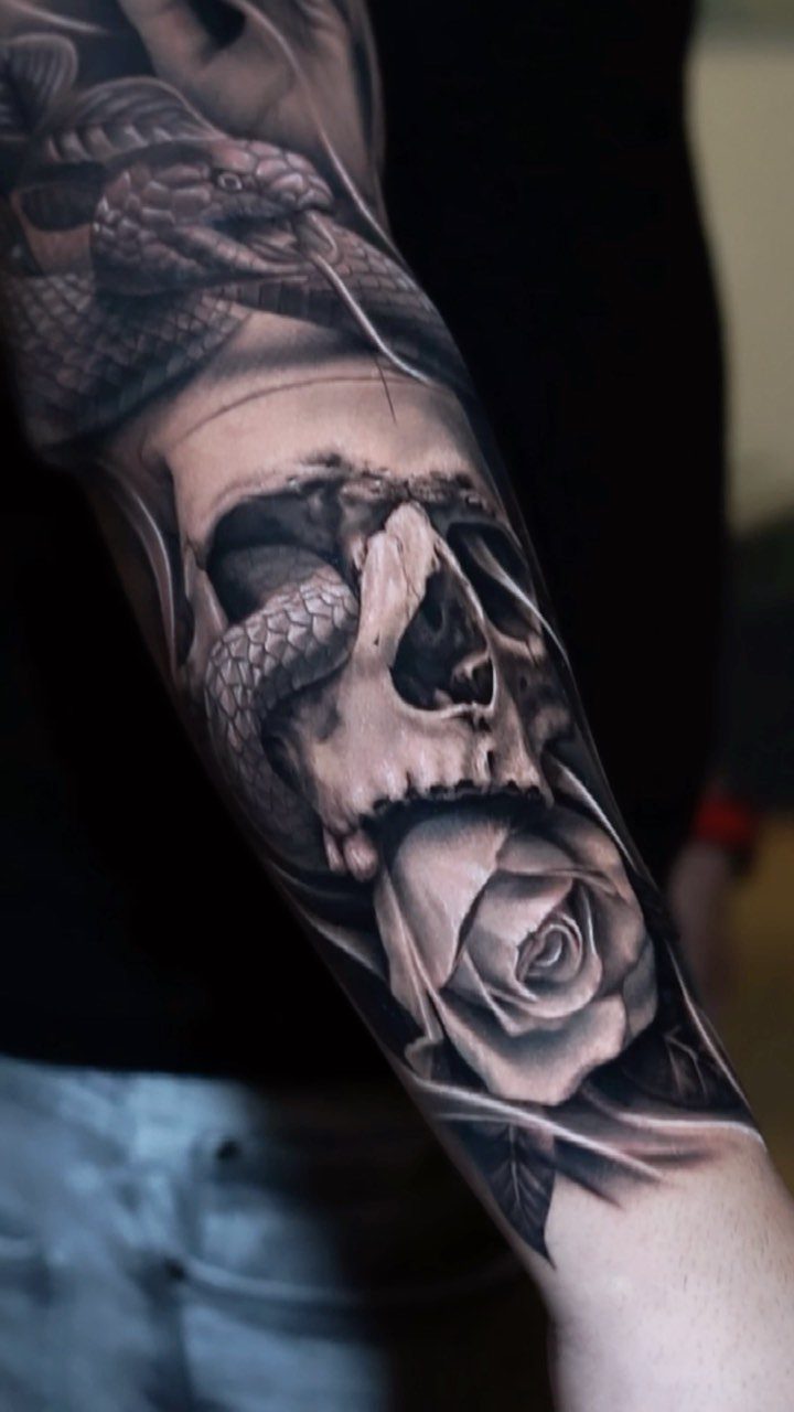 Tattoo of a realistic skull entwined with a snake and a rose
