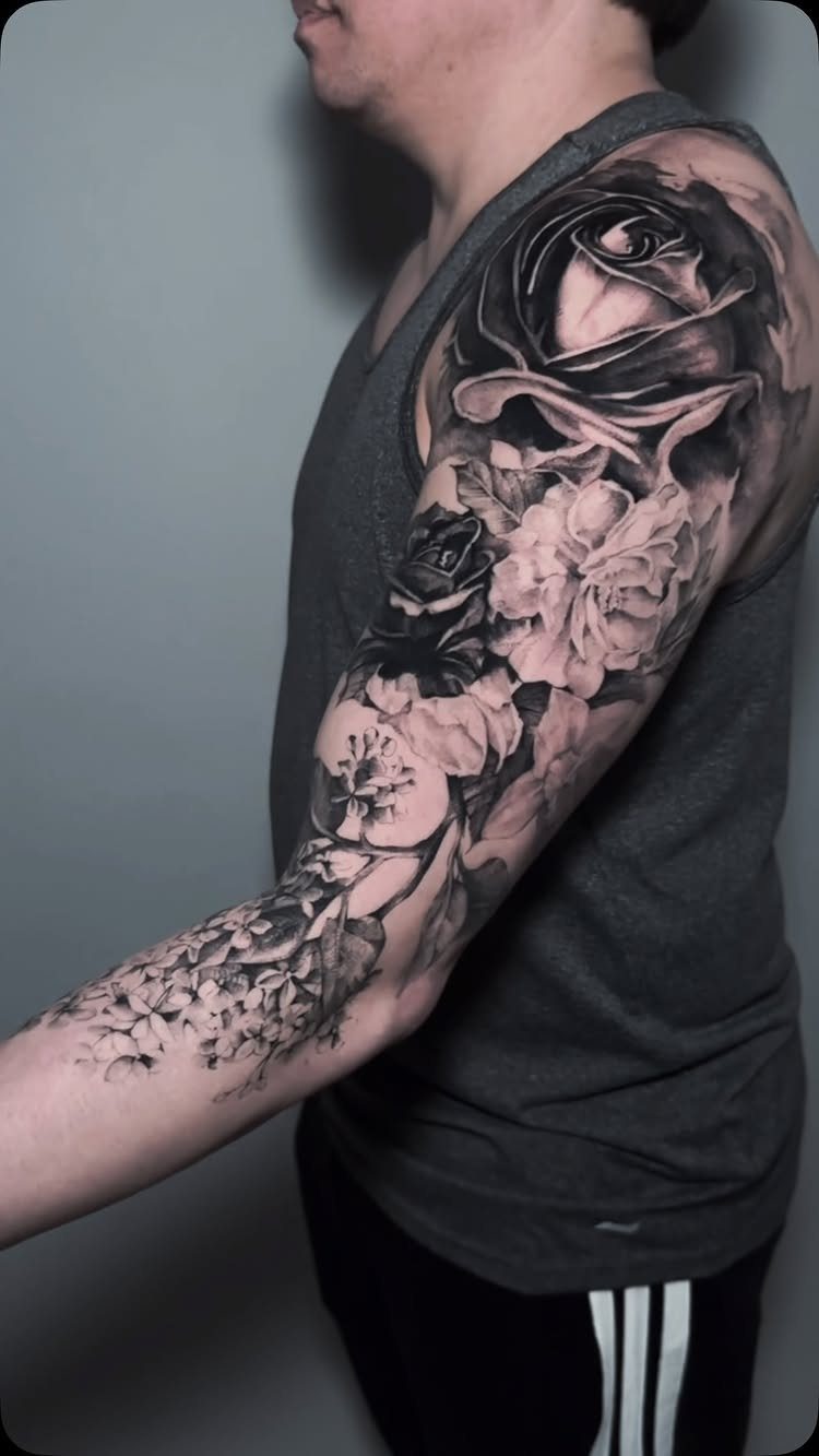 Black and grey rose sleeve tattoo covering a person's entire arm and shoulder.