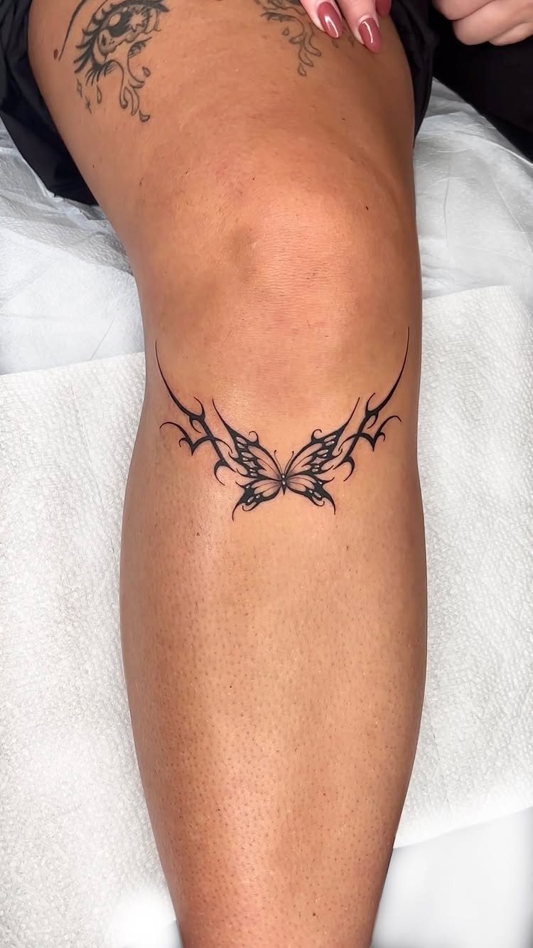 Tribal butterfly tattoo with bold black lines on a person's lower leg.