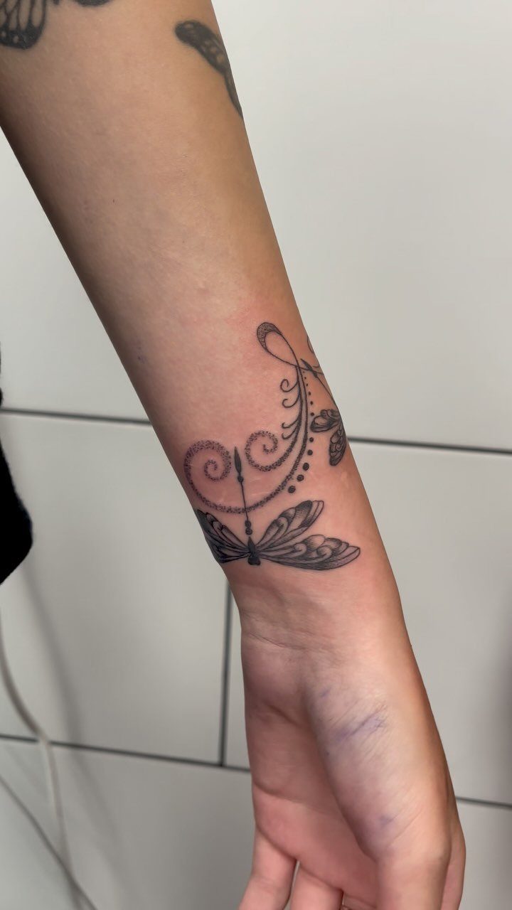 Dragonfly tattoo with dot work and swirls on a person's inner wrist