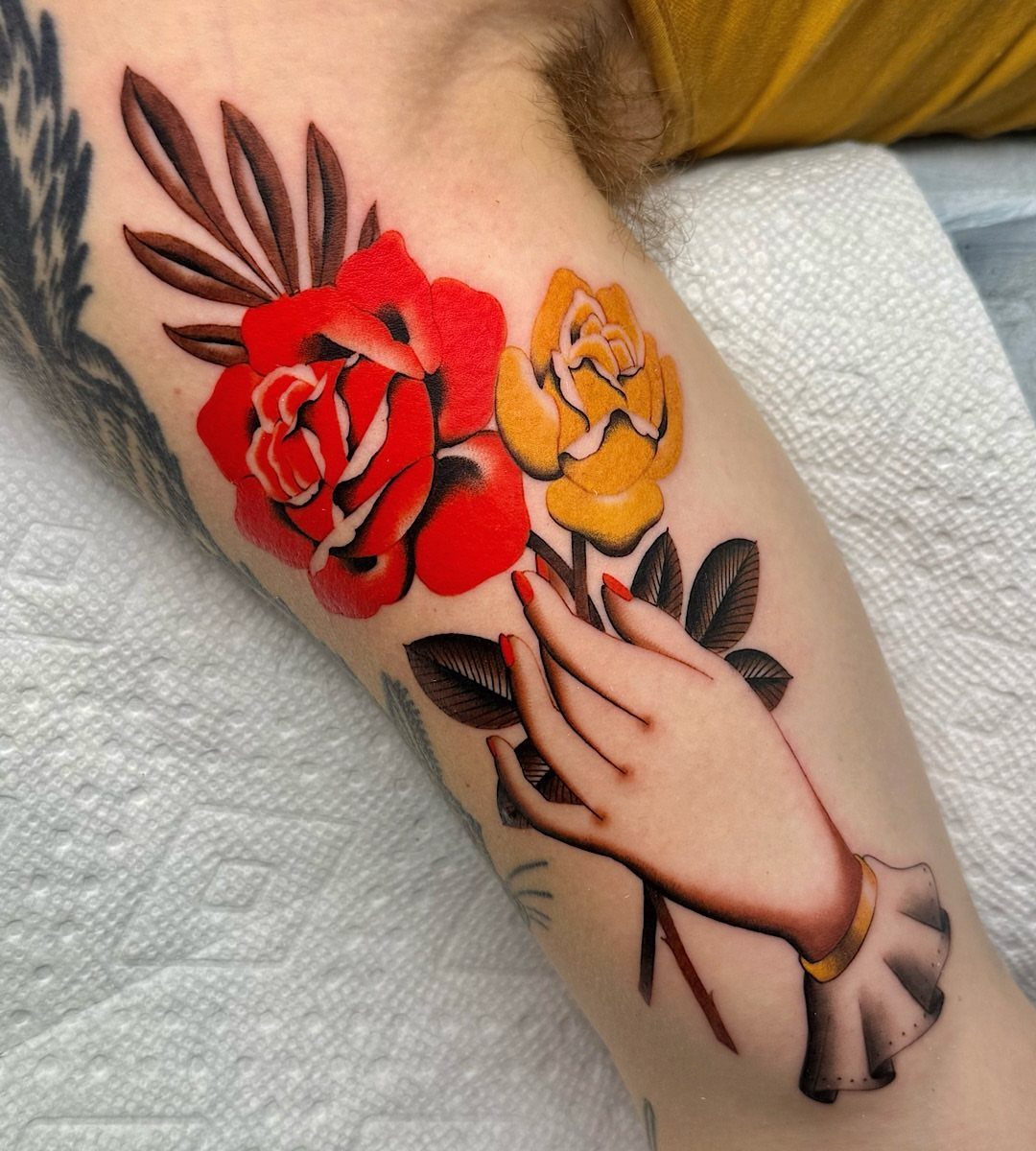 Traditional tattoo of a hand holding a red and yellow rose bouquet