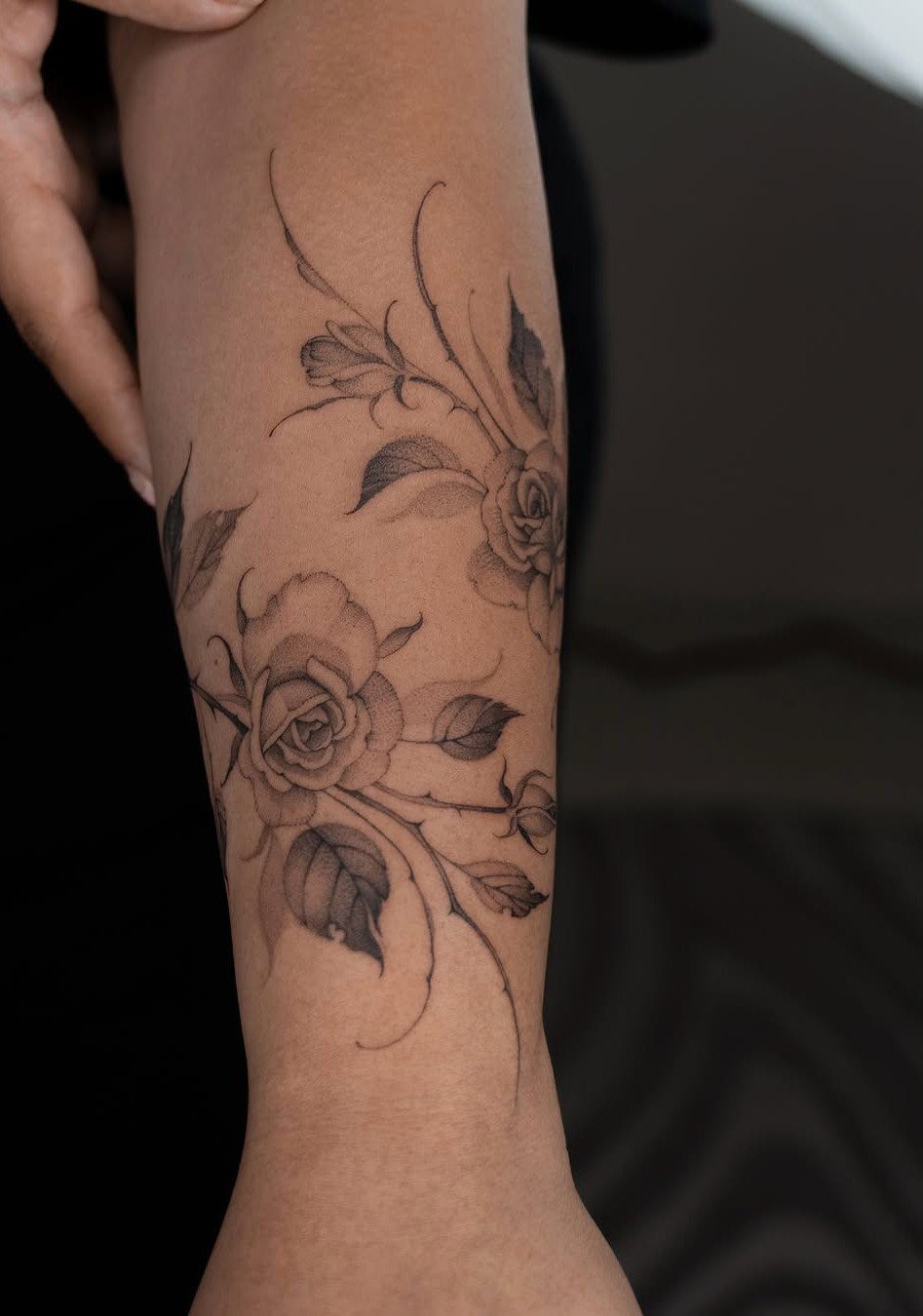 Rose and vine tattoo with detailed shading on a person's forearm