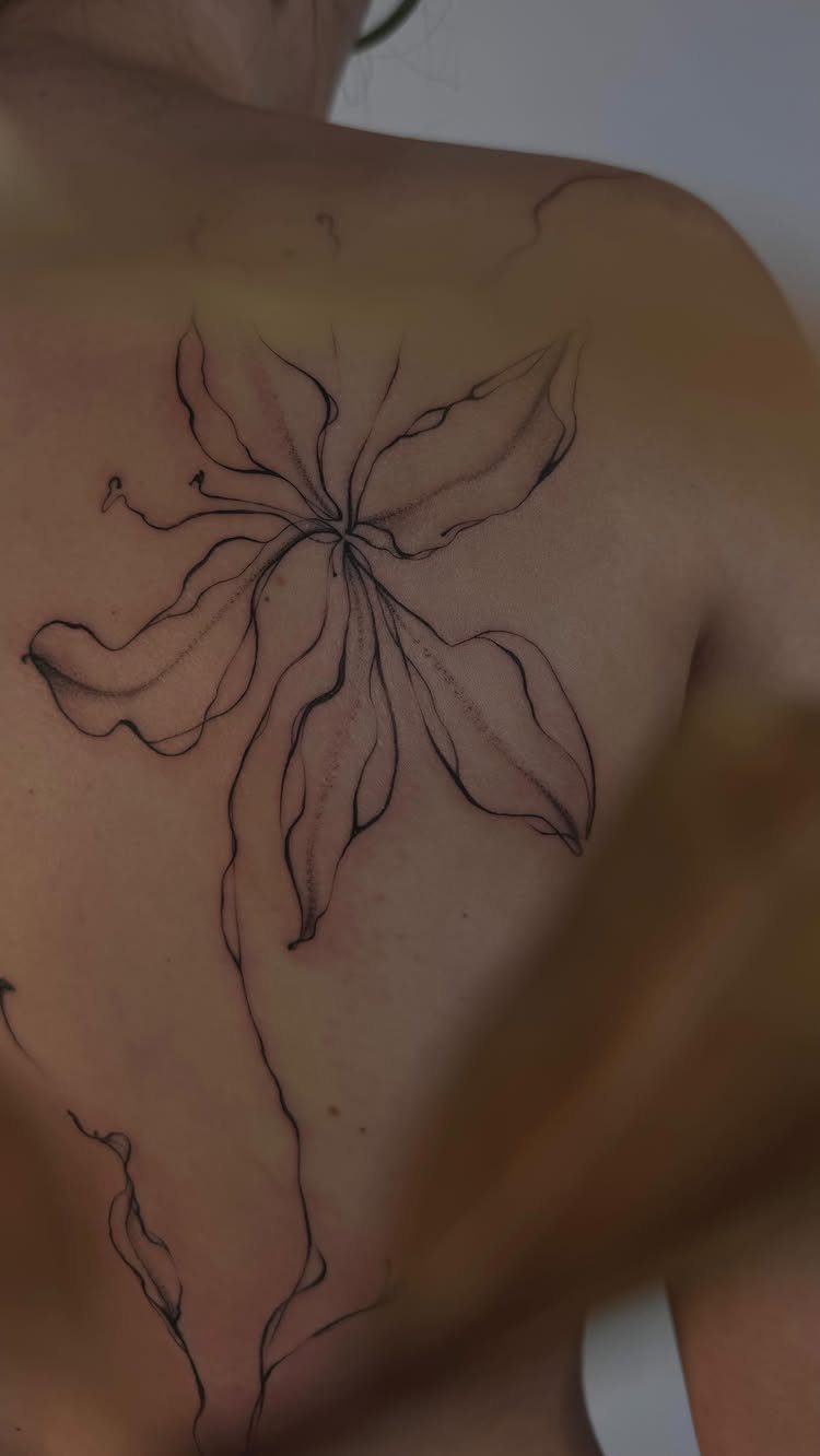 Abstract floral line tattoo on a person's upper back and shoulder
