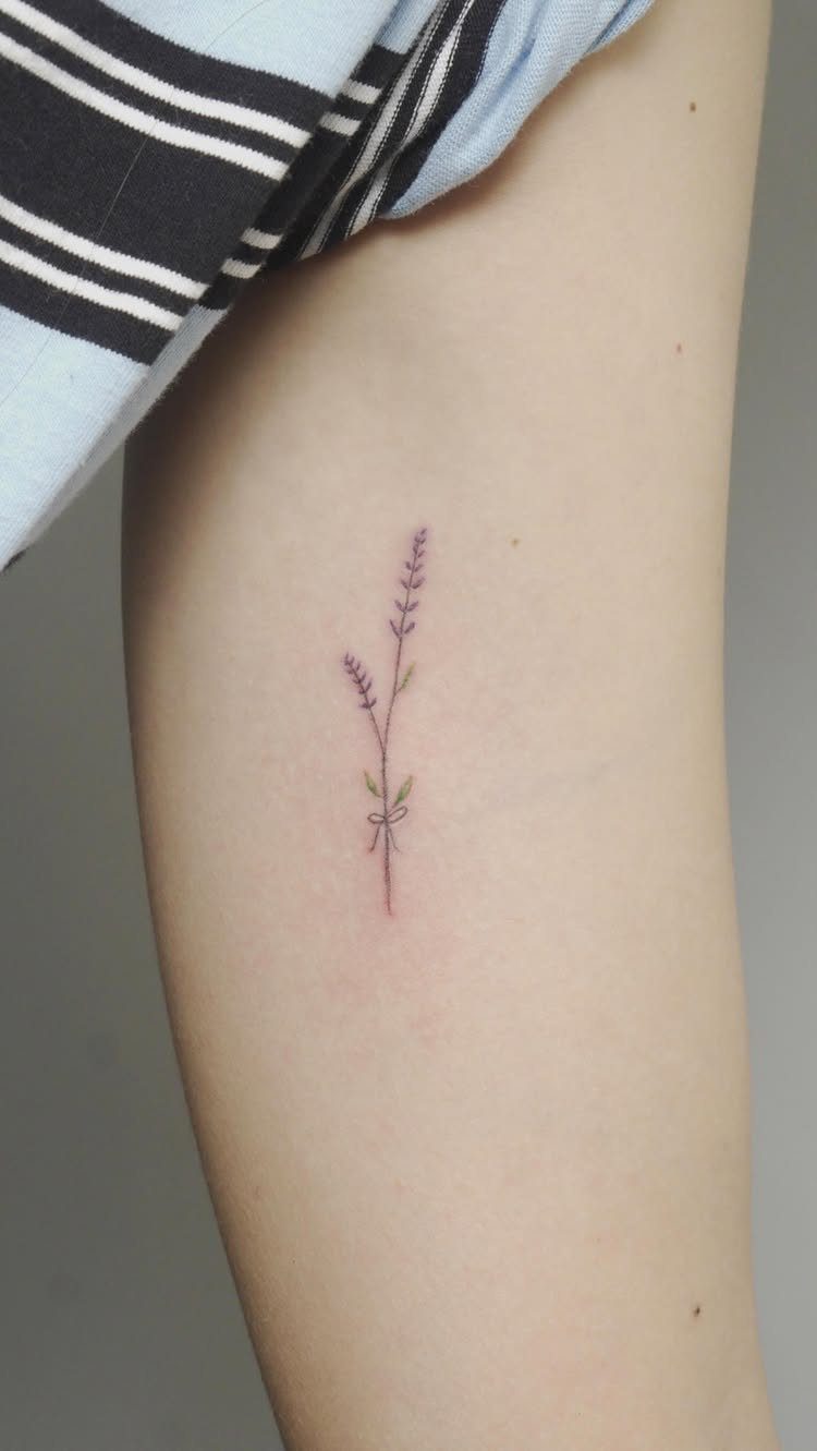 Lavender sprig tattoo with a small bow on a person's pale skin