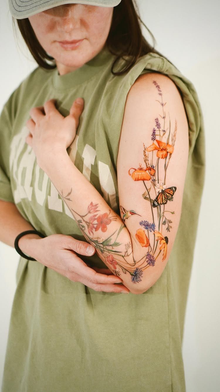 Colorful wildflower tattoo with a monarch butterfly on a woman's arm