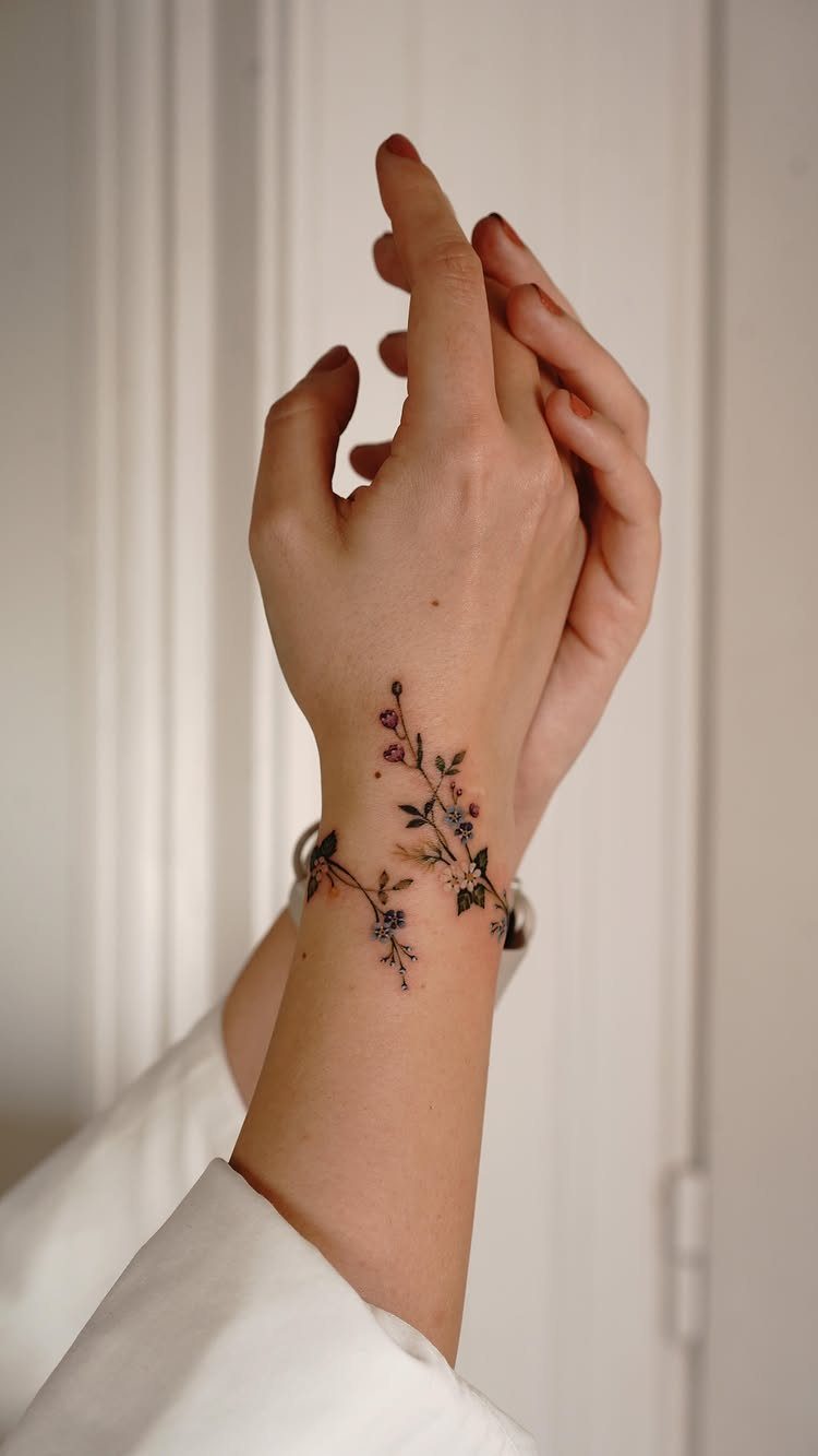 Colorful floral tattoo on a wrist with small red and blue flowers.