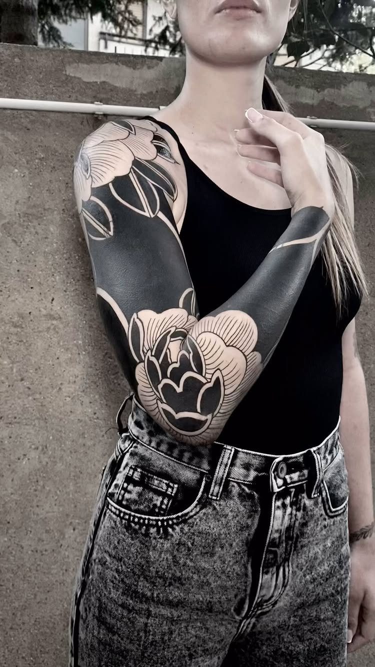Blackwork floral tattoo sleeve on a person's arm with bold black ink flowers