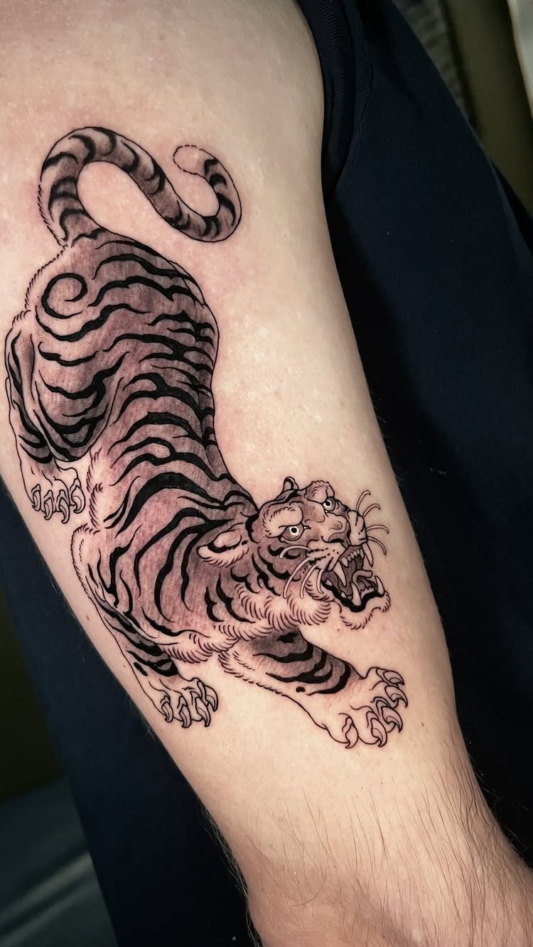 Roaring tiger tattoo in Japanese style on a person's upper arm.