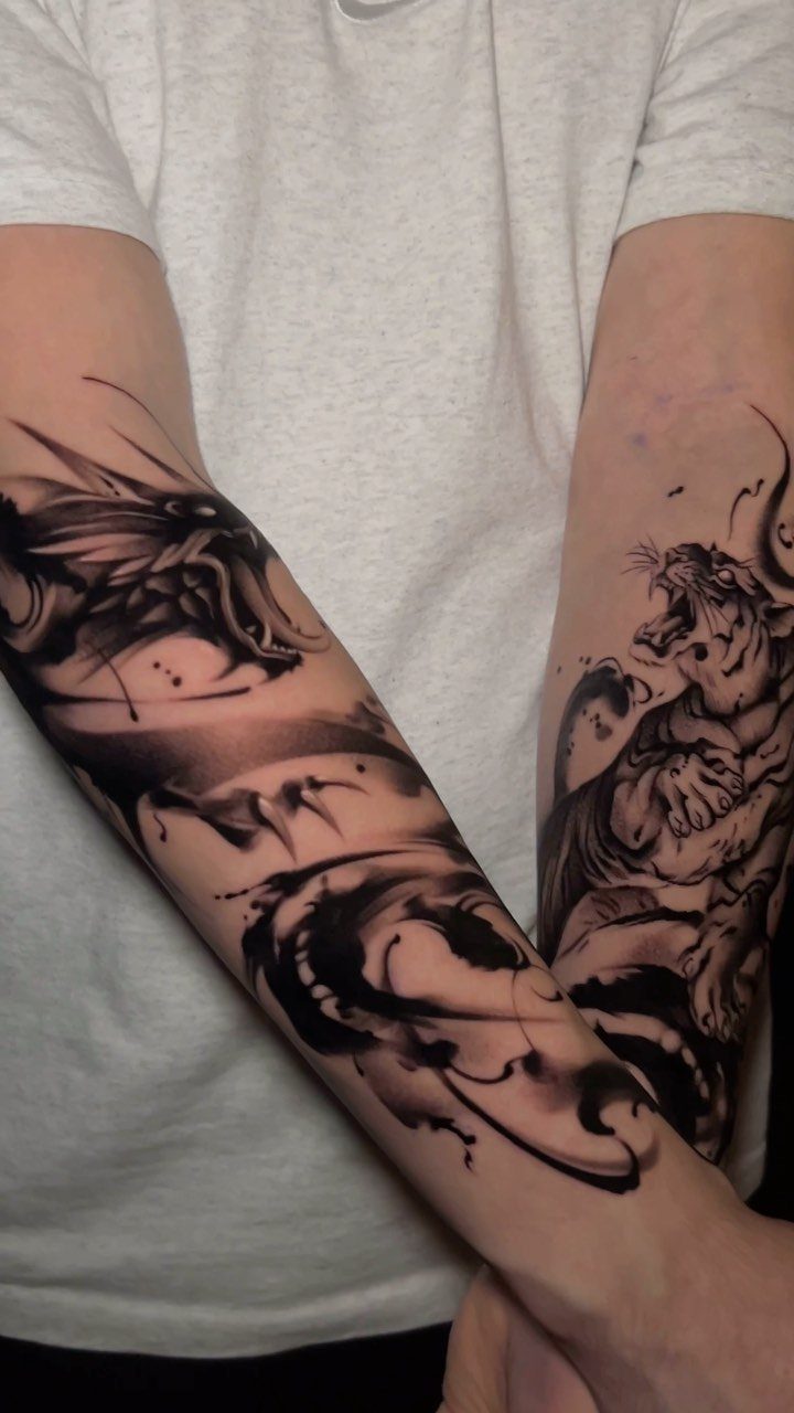 Black ink tattoos of a dragon and a roaring tiger on forearms