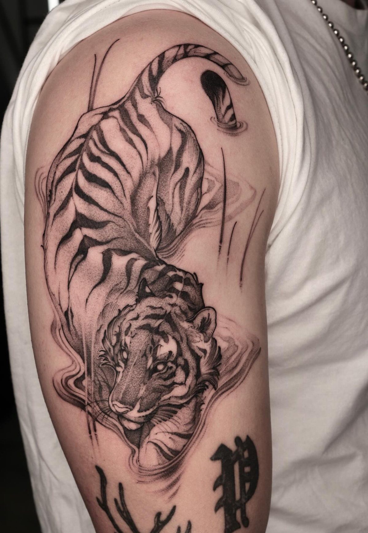 Tiger tattoo on an arm showing the animal diving through swirling water ripples.