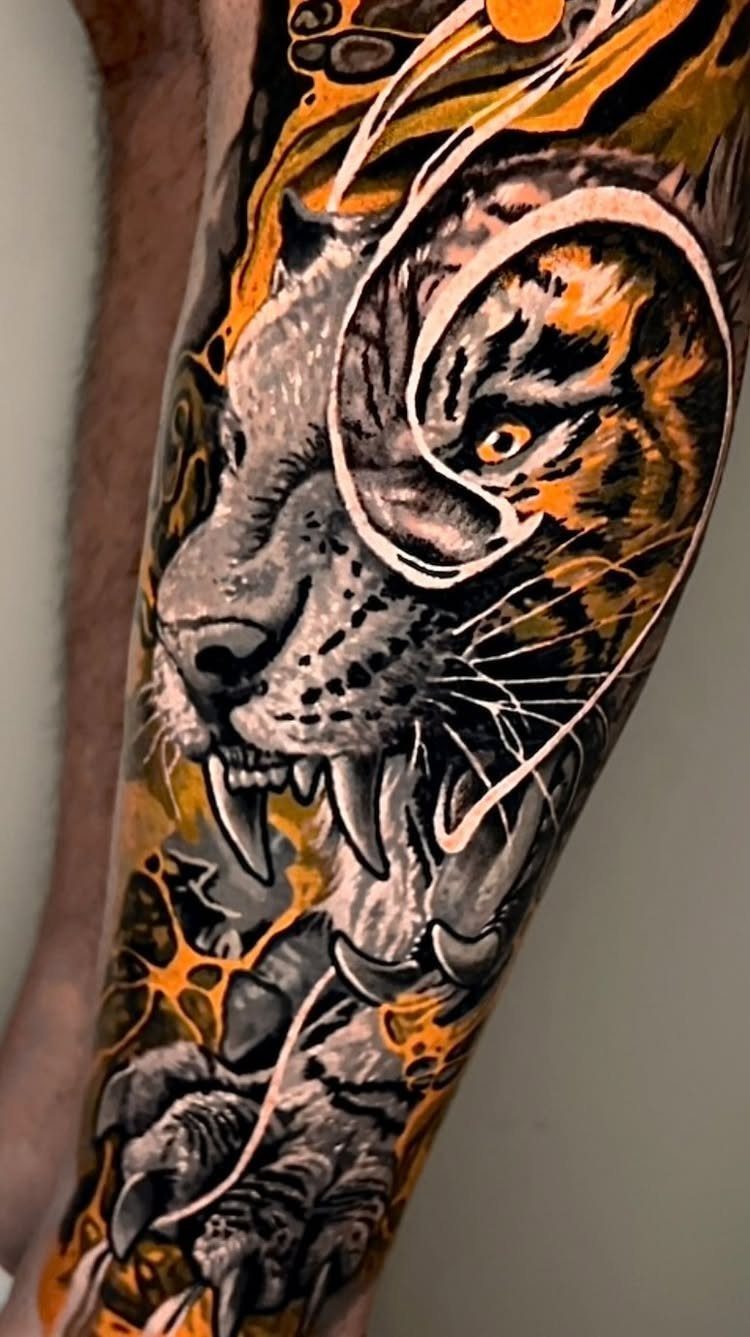 Roaring tiger tattoo on a forearm with orange and black ink details.