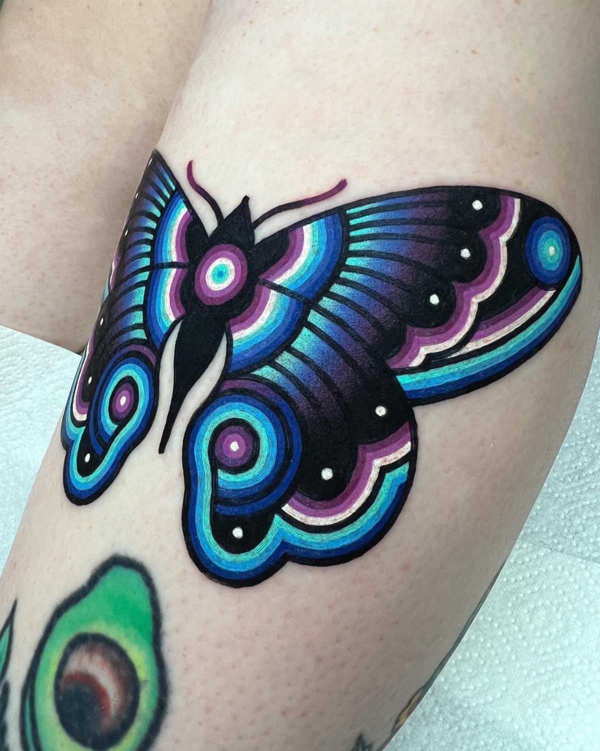 Colorful butterfly tattoo with blue and purple concentric patterns on human skin