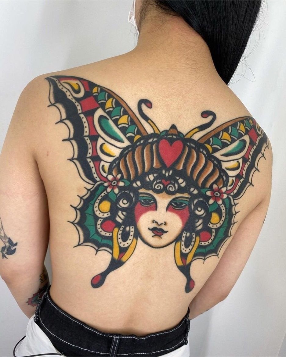 Traditional butterfly tattoo on a back featuring a woman's face and colorful wings